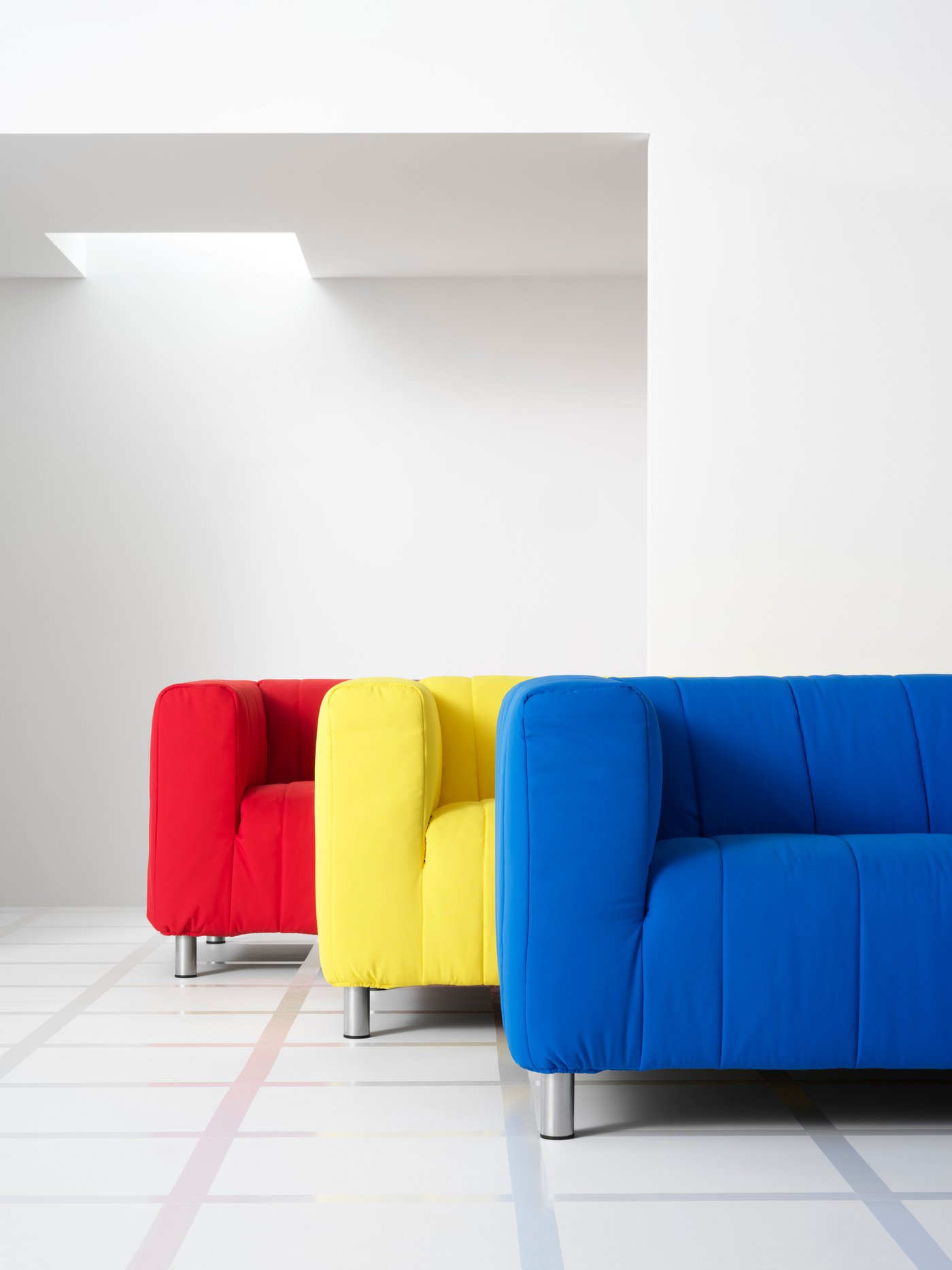 Red, yellow and blue KLIPPAN sofas standing next to each other.