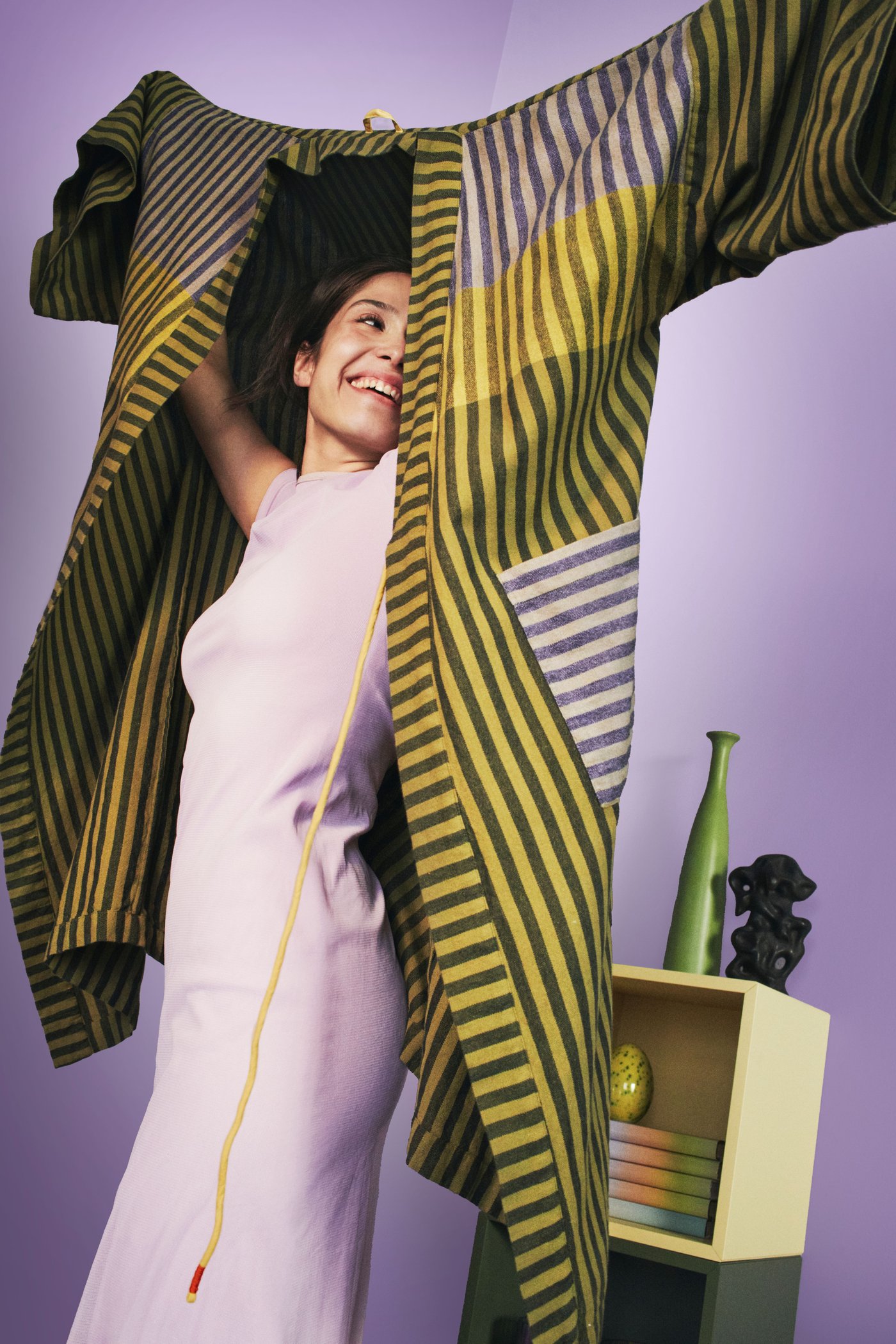 A person is dressing up with a bath robe from this collection. The wall behind is in light purple color. 