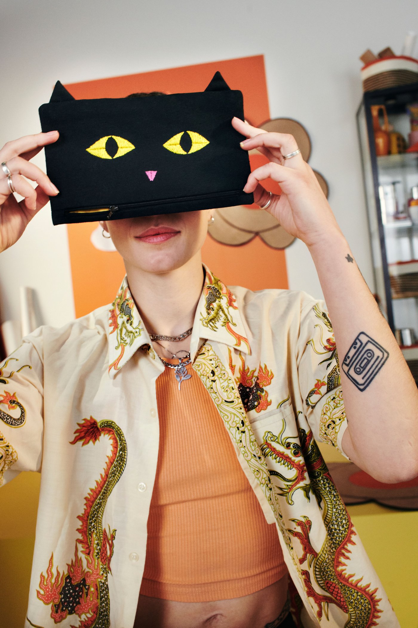 The image shows a young person is holding a pouch in black cat pattern from this collection, which partially covers his face.