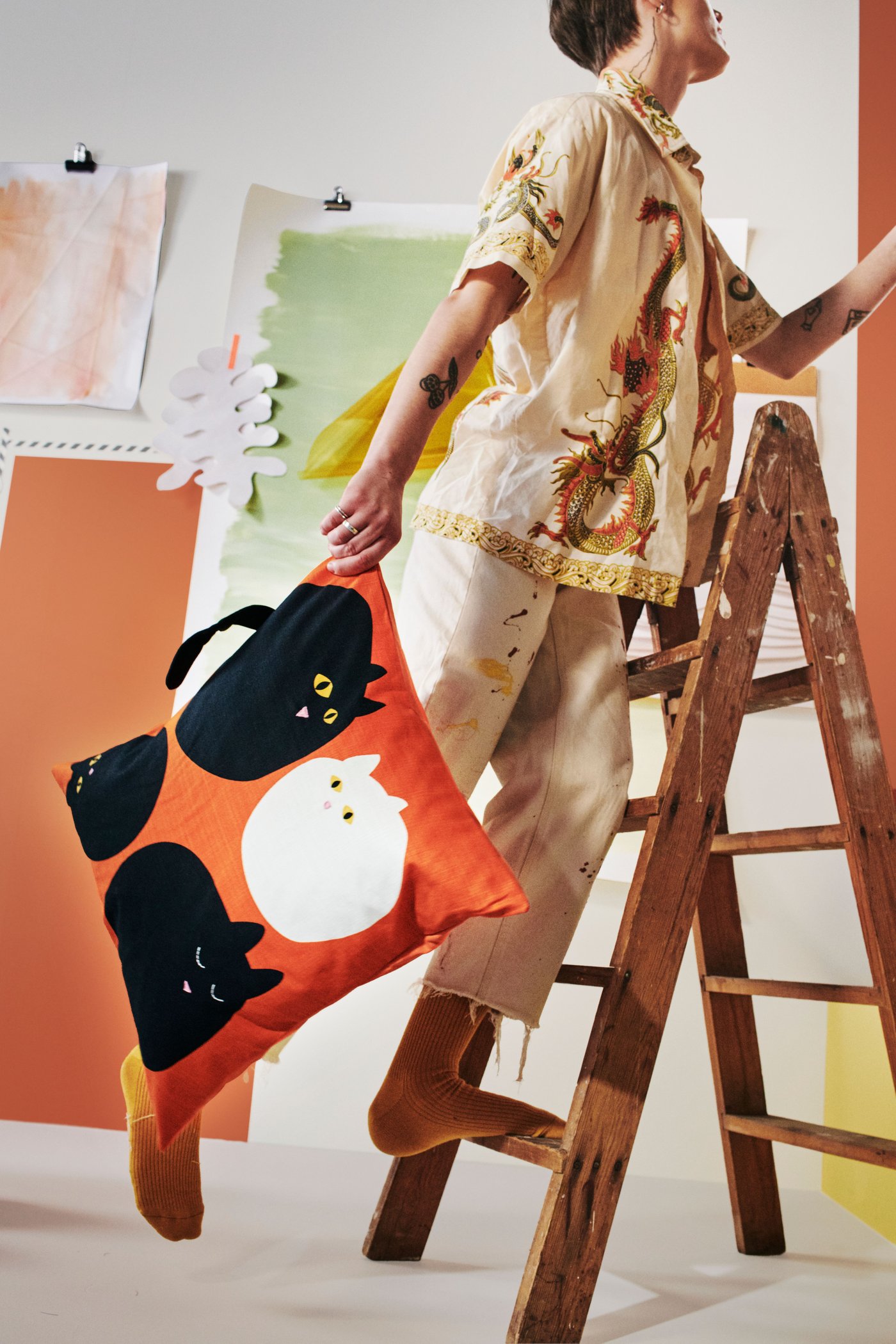 The image shows a young person is climbing on a ladder, holding a cushion from this collection. 