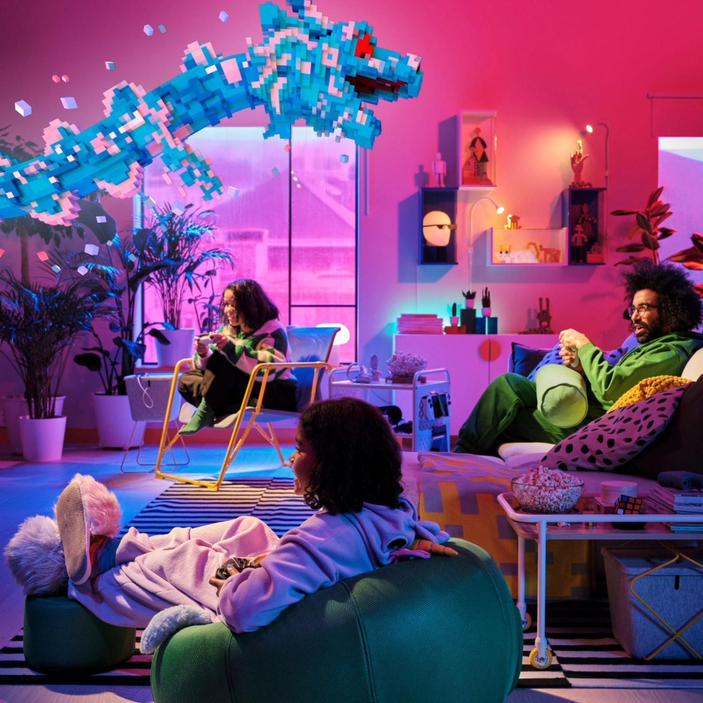 Two children are sitting in a green inflatable chair and a yellow easy chair, faced towards a television where an animated blue dragon arises from the screen. A man is sitting in the sofa next to them with a controller, playing.