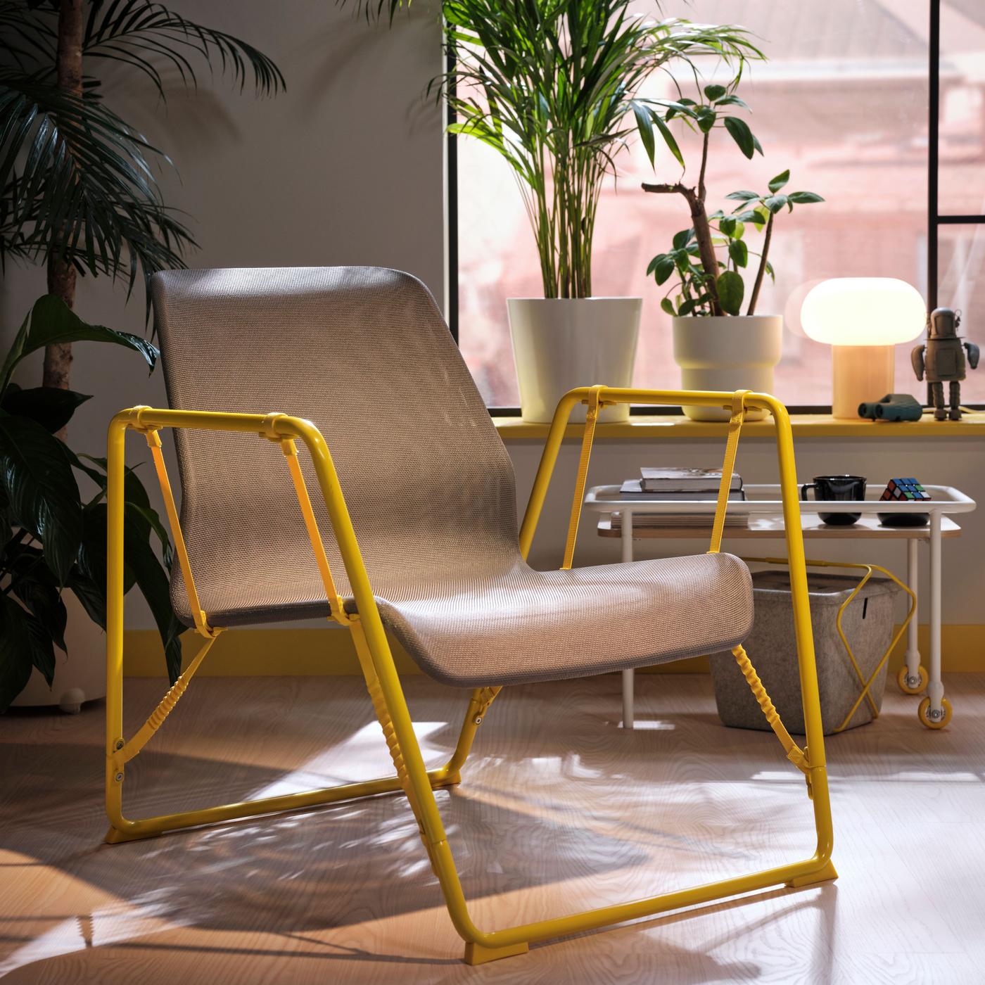 A yellow chair with bright beige mesh is standing in a bright living room with plants.