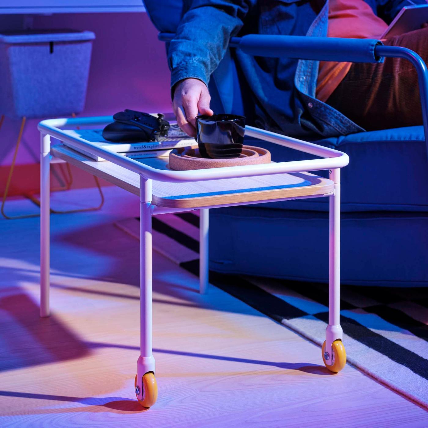 A hand reaches over to a side table to grab a mug.