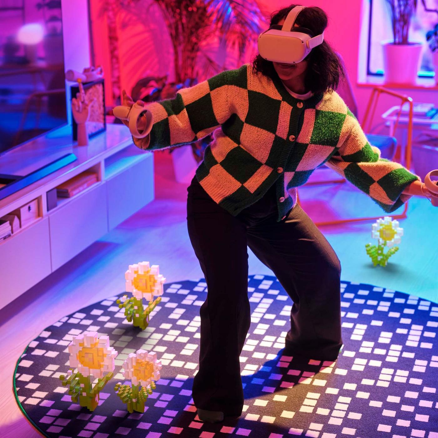 A girl stands on a rug from the BRÄNNBOLL collection. She is wearing VR goggles and playing a game.