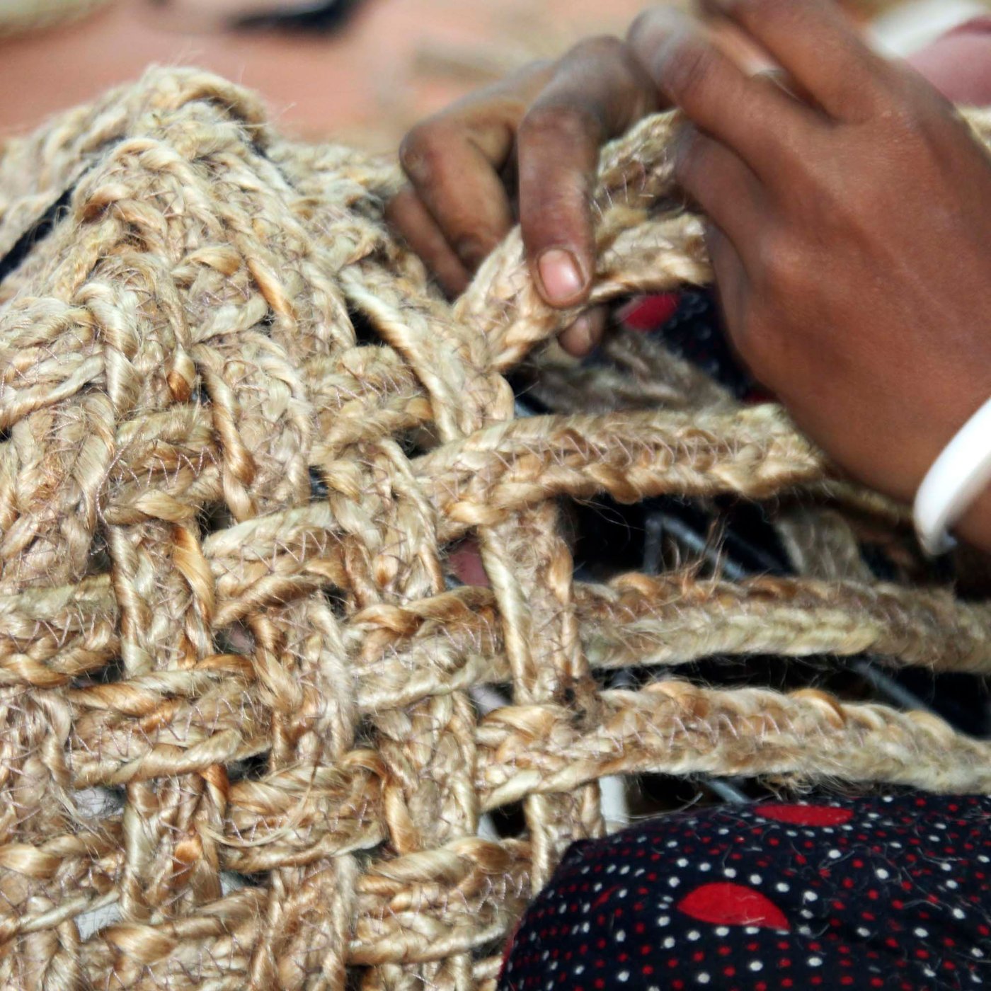 A pair of hands weaving a jute MÄVINN basket.