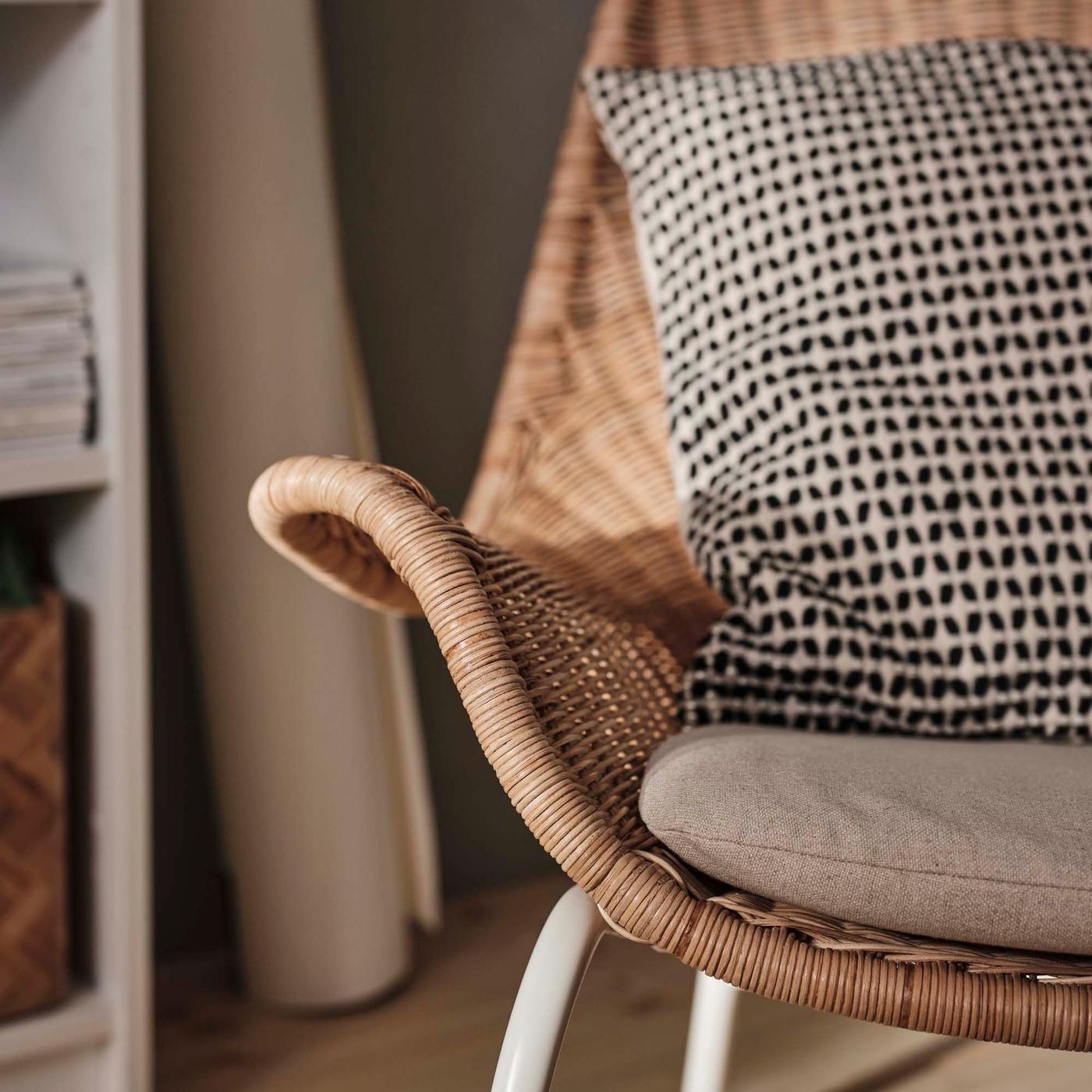 A close-up shot of a FRYKSÅS chair in rattan with a black patterned cushion.
