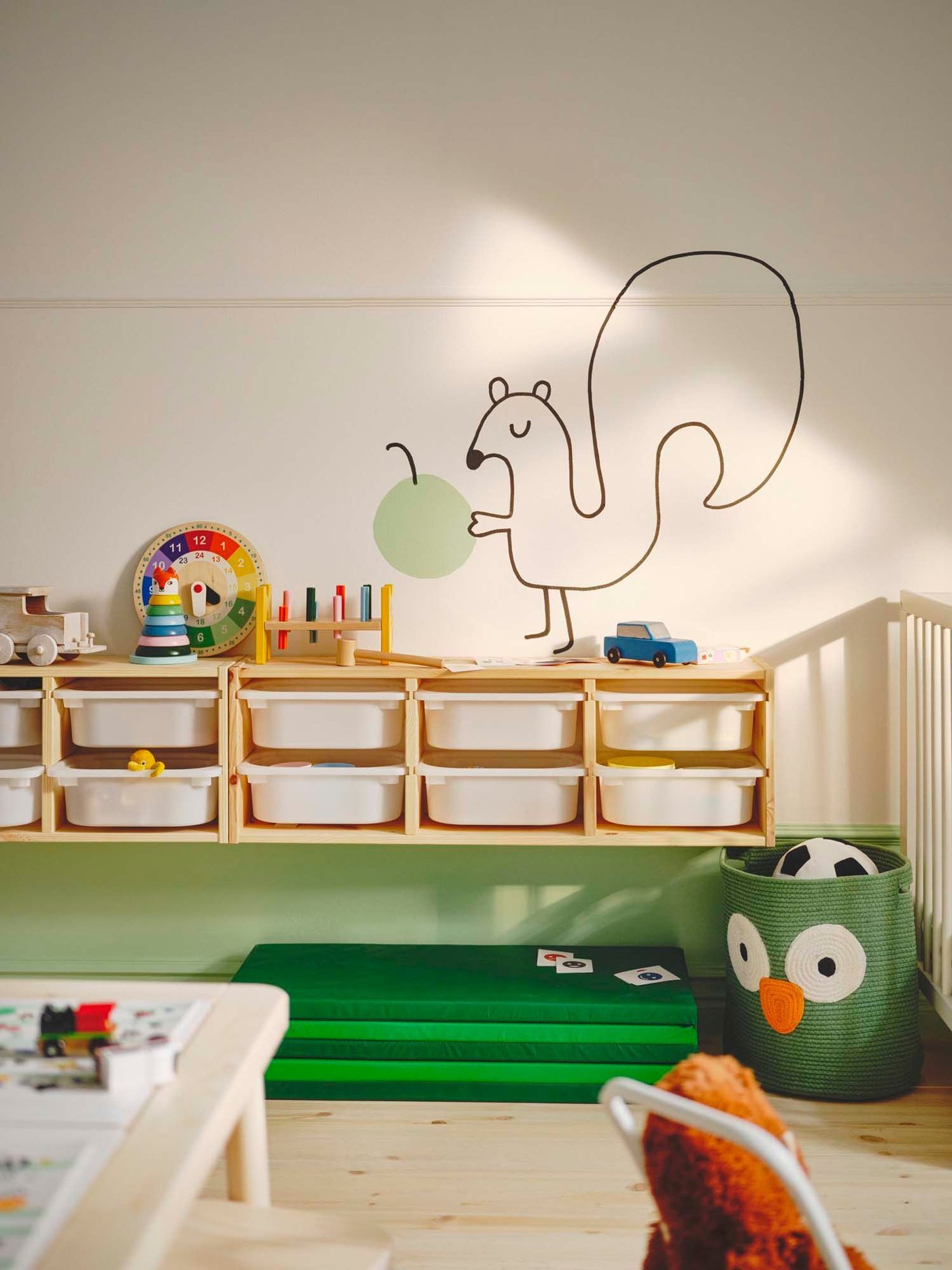 The wall of a toddler room featuring a TROFAST storage unit with drawers hanging from the wall and a drawing of a squirrel above.