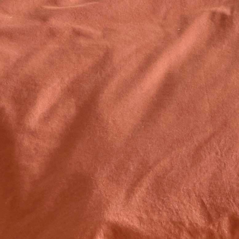 A close-up of a rust coloured cotton duvet cover.