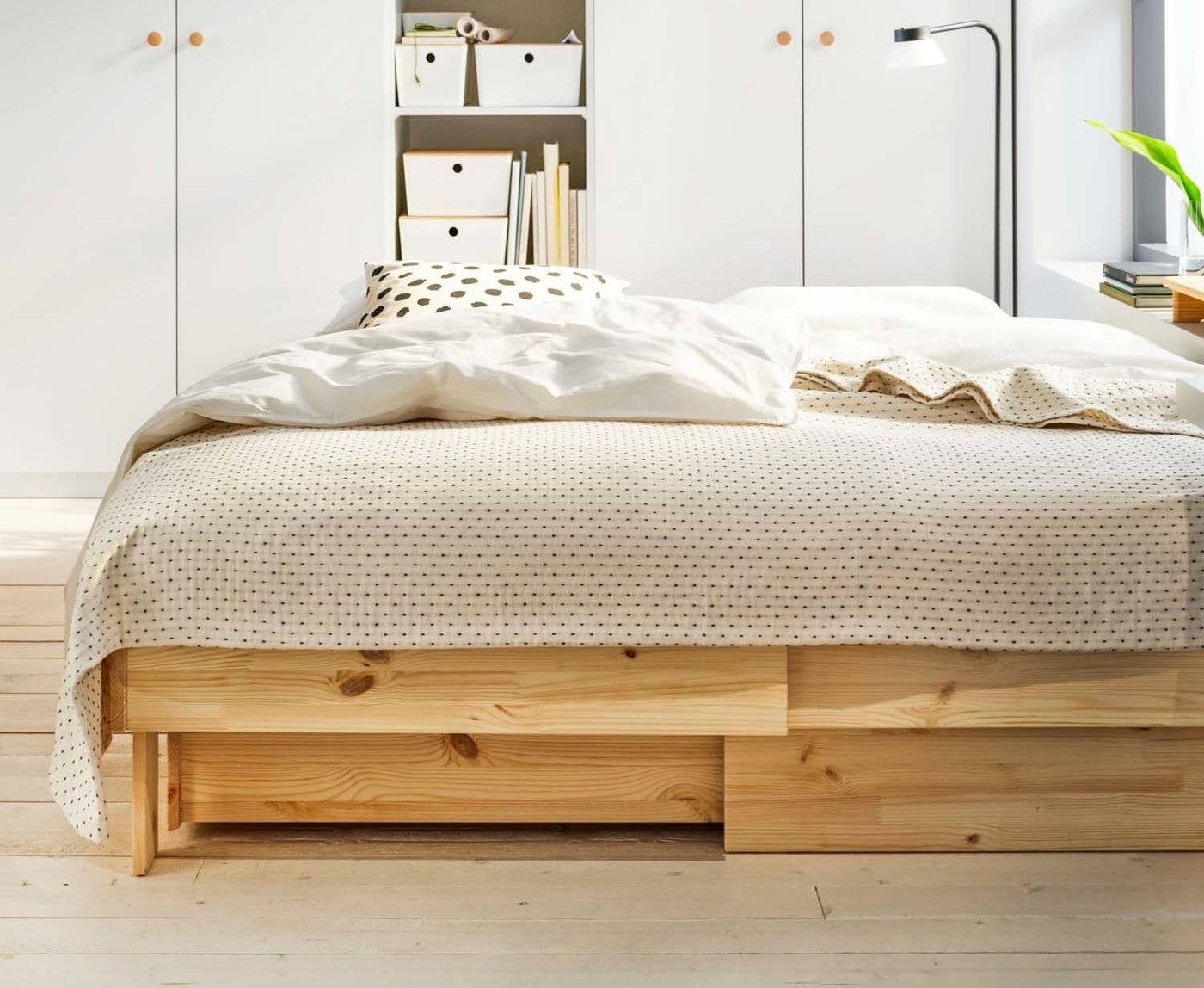 A dressed GLAMBERGET extendable bed with storage in front of white/white PAX / FORSAND wardrobes in a bedroom setting.