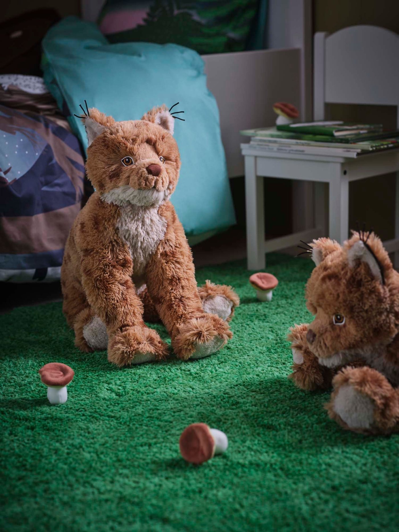 Two lynx/orange brown SKOGSDUVA soft toys on a green SKOGSDUVA rug, high pile.