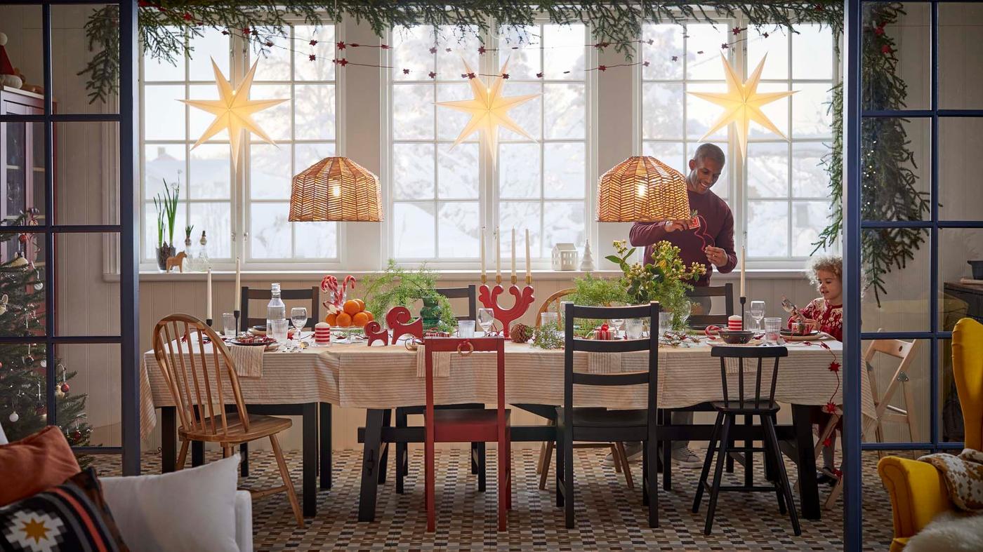 A dining area with a child and adult behind a dining table with VINTERFINT candles and candle holders, and other decorations.