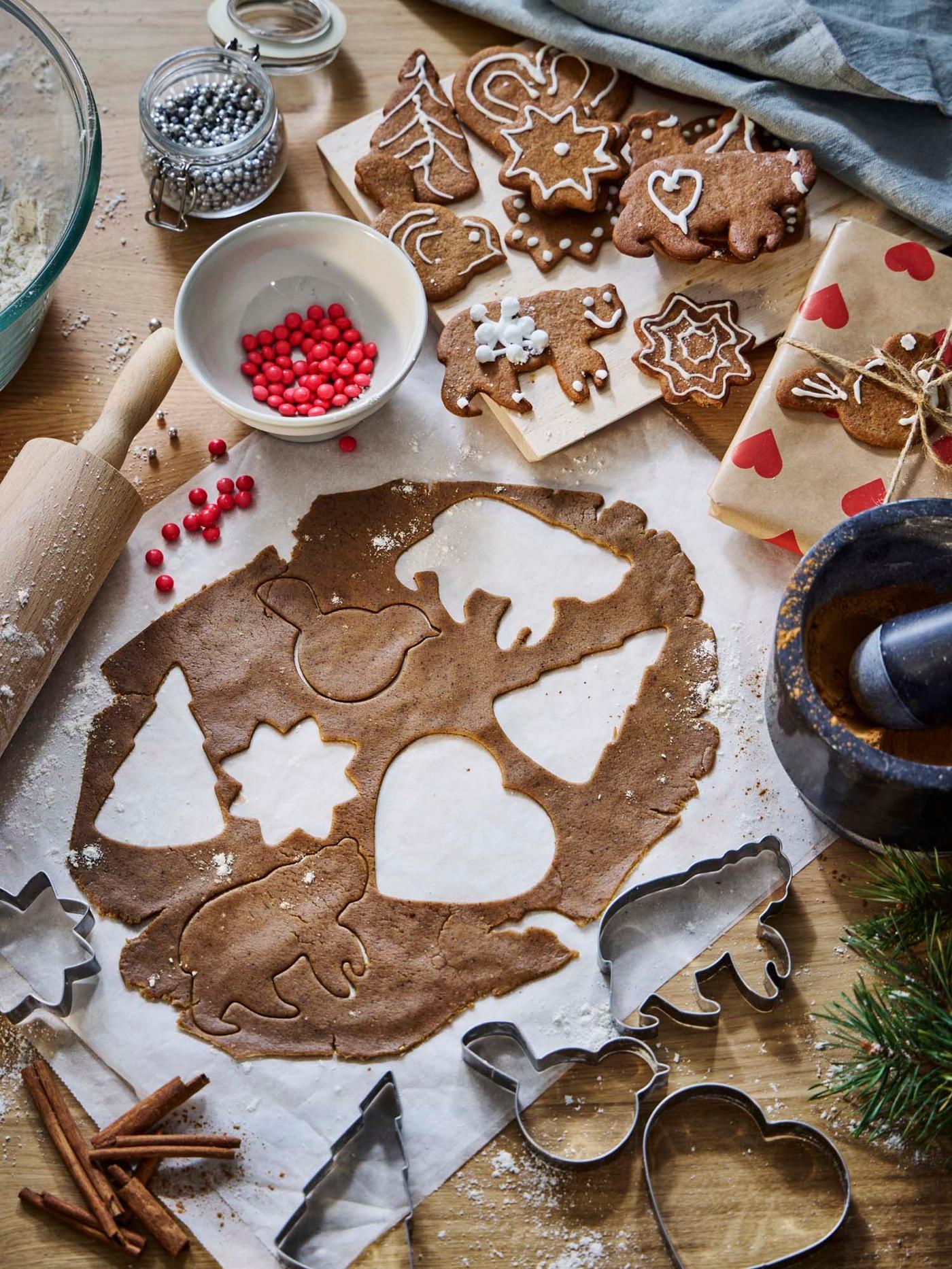 Overhead view of a kitchen surface with rolled-out gingerbread dough and stainless steel VINTERFINT pastry cutters.