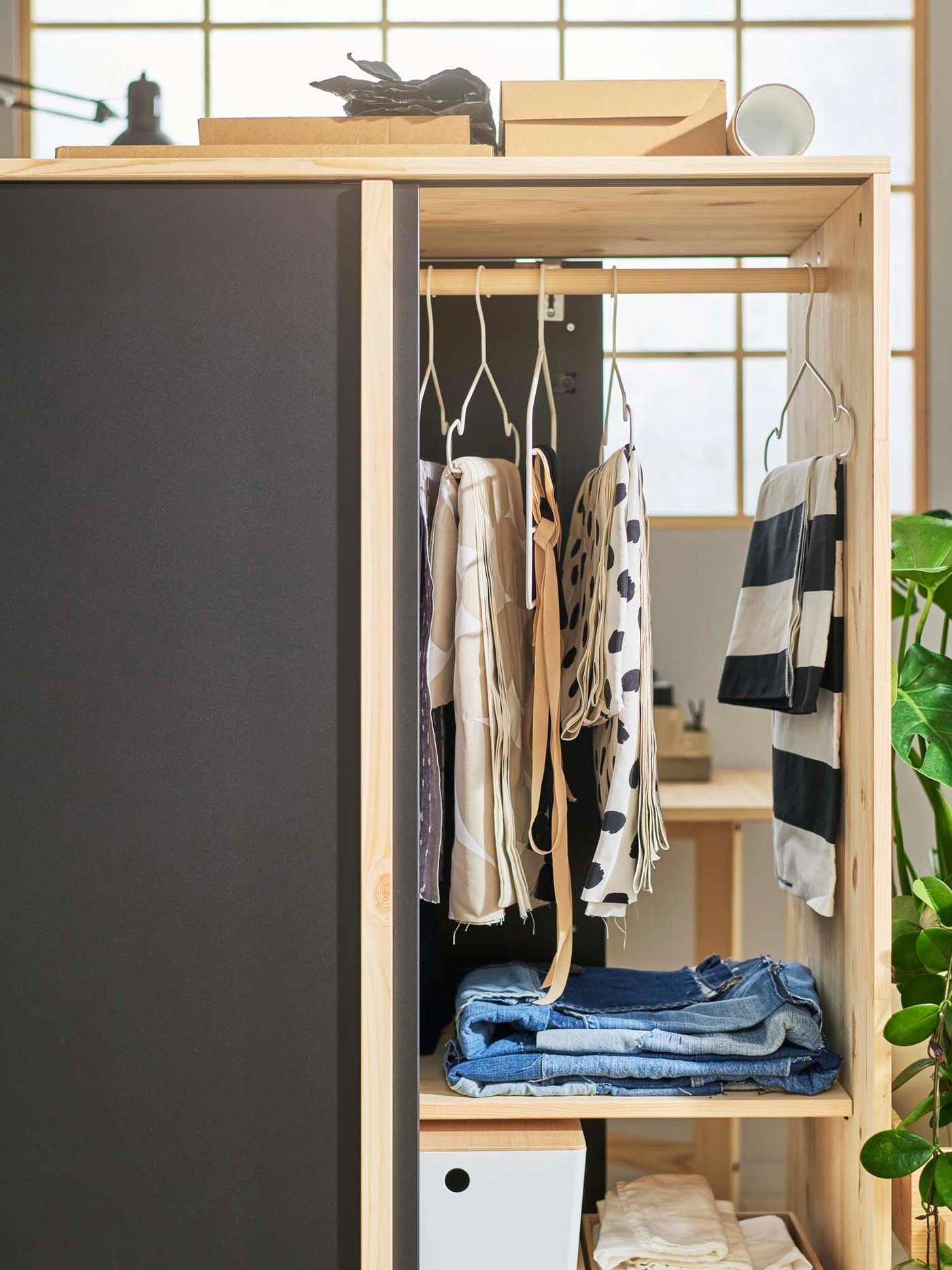 An open pine/black GLAMBERGET wardrobe with 3 sliding revealing clothes on hangers inside.