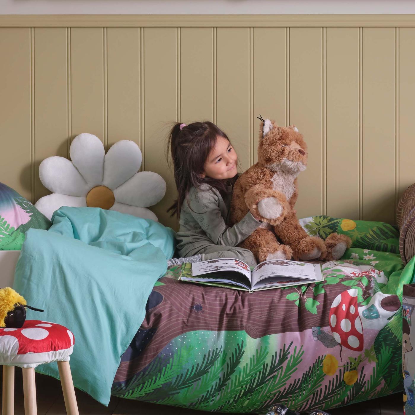 A child playing with a toy, sitting on her bed.