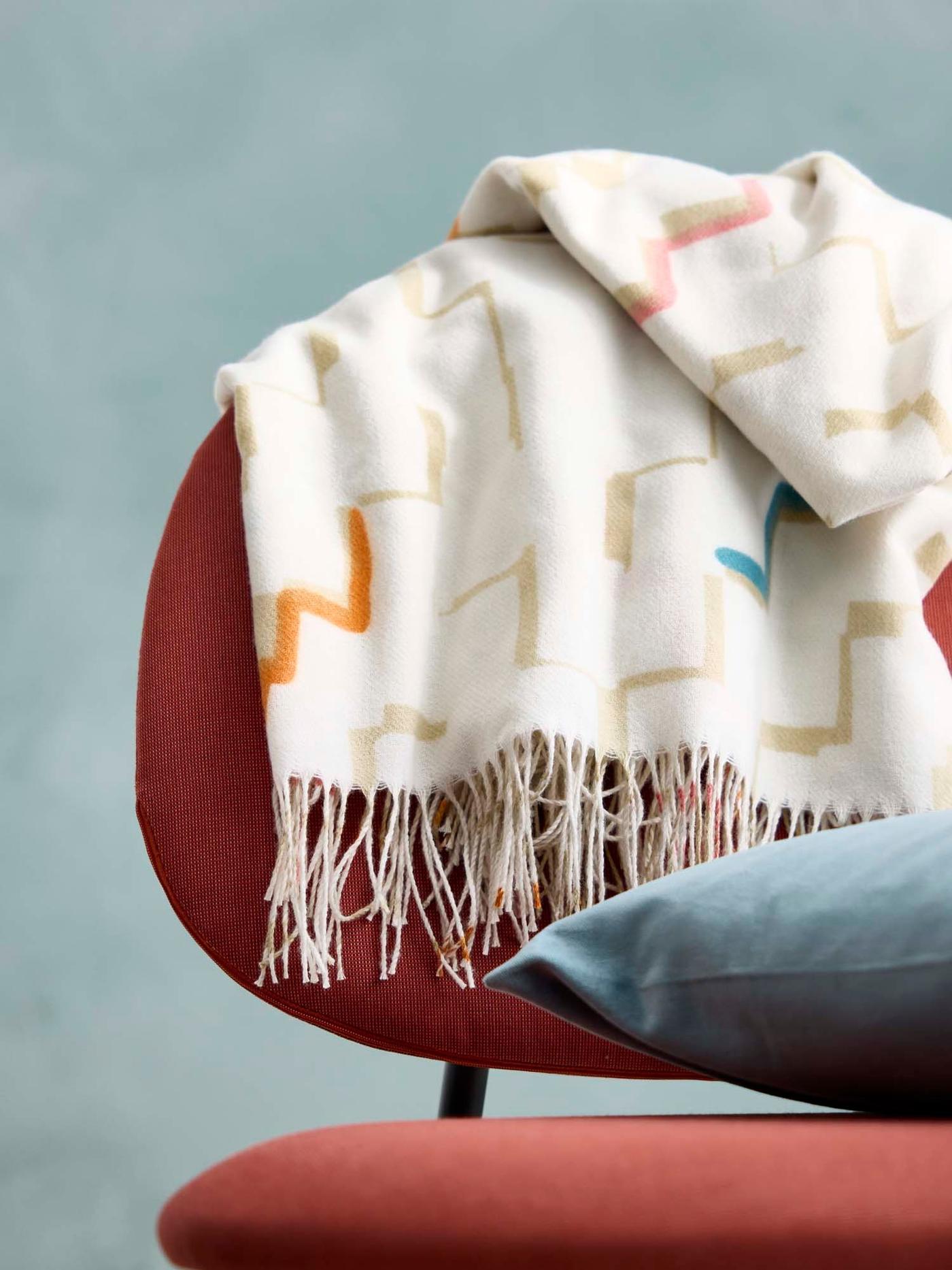 A red GÄVLE easy with a tassled throw over the back and a blue cushion on the seat.