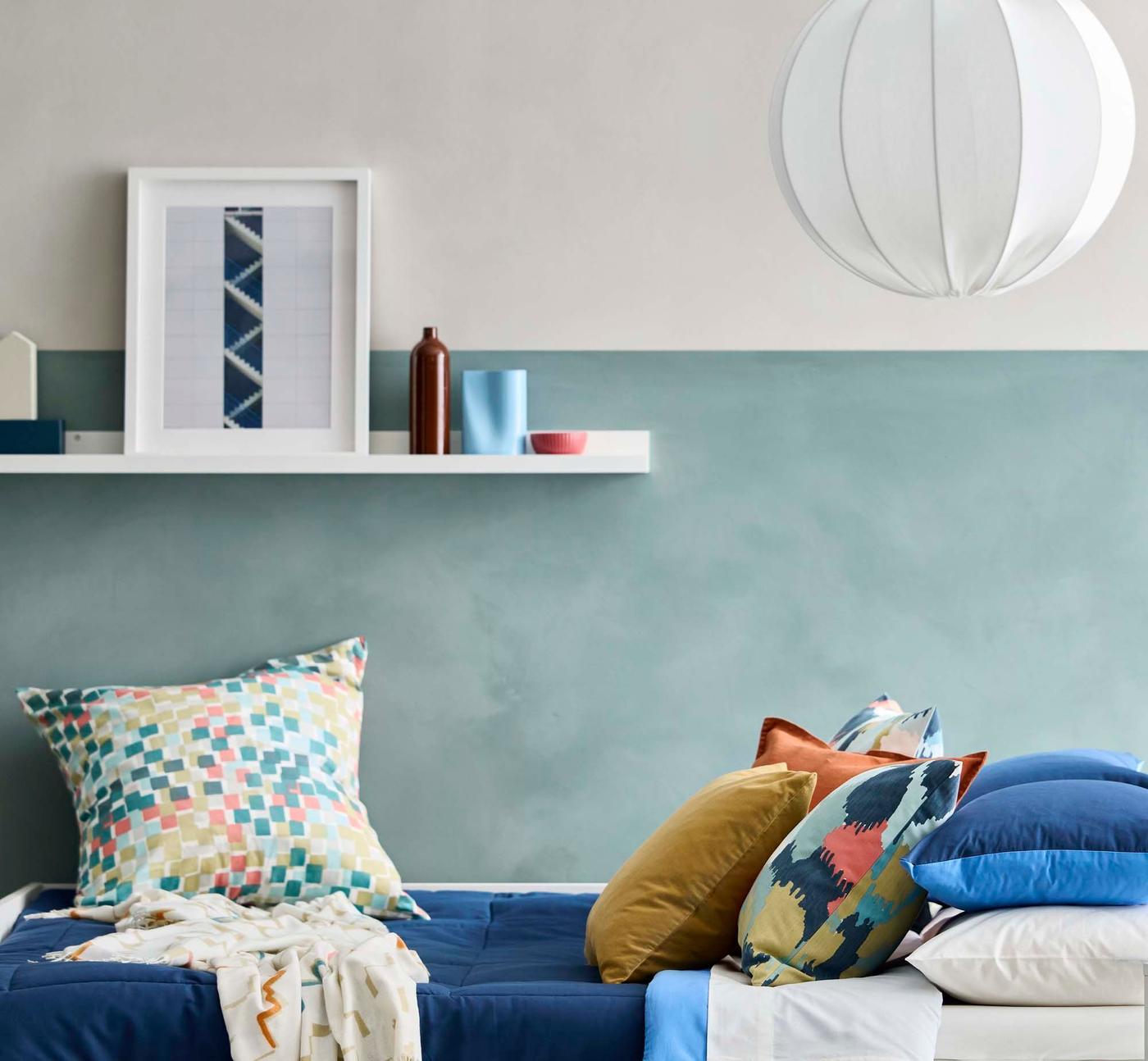 A shelf above a bed. The shelf is filled with a picture and objects.