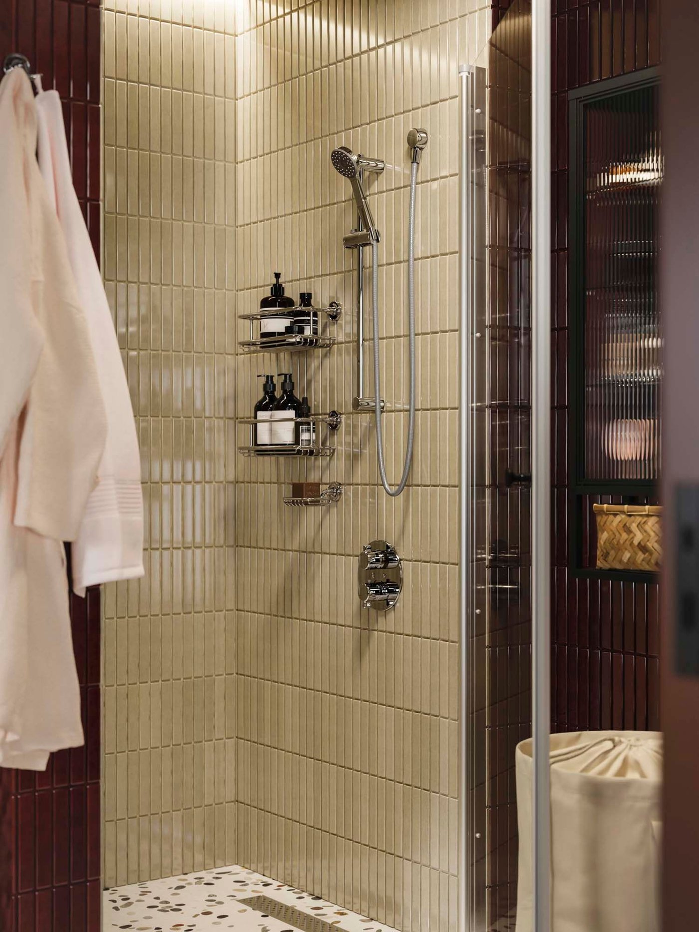 A beige tiled shower area with two shelves filled with shower products.
