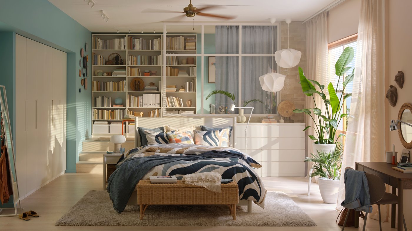A bedroom with a large wall length white PAX storage unit behind a bed.
