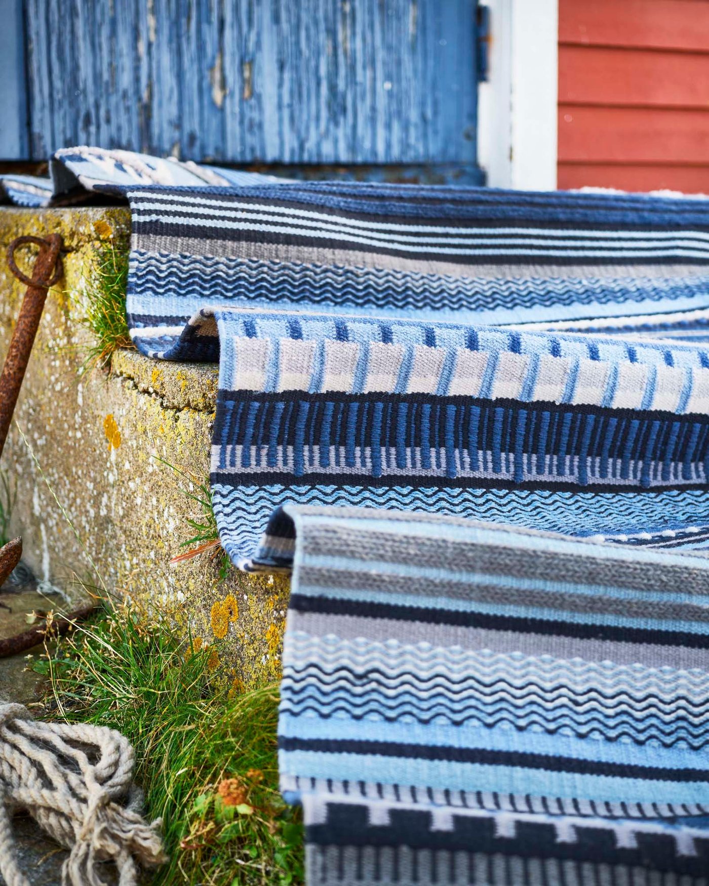 A blue patterned HARSVANS rug is draped over the stone steps of a fisherman's hut.