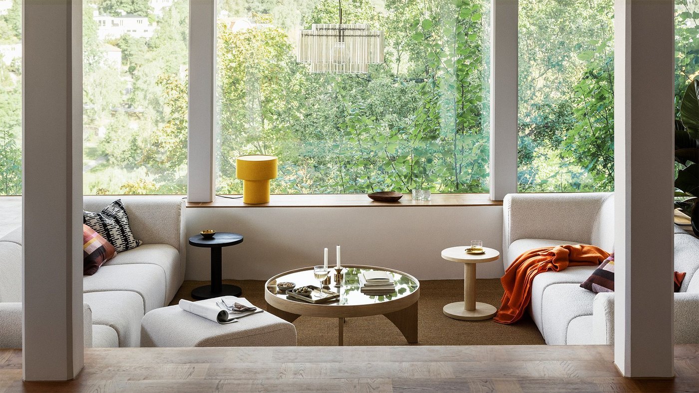 A living room with large windows in the background and two sofas facing each other in the foreground.