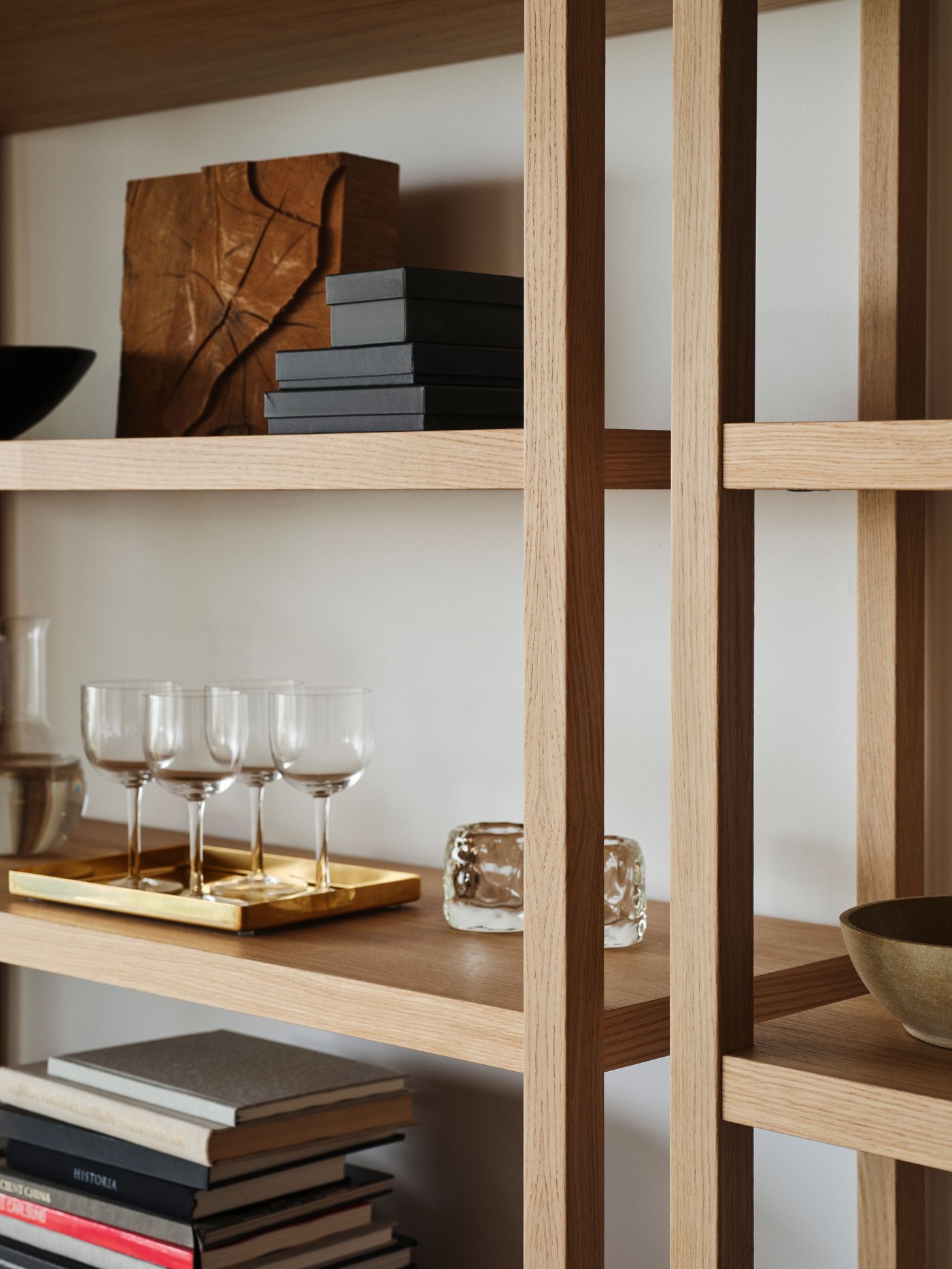 Closeup of a wooden shelf with a tray of wine glasses and books on.