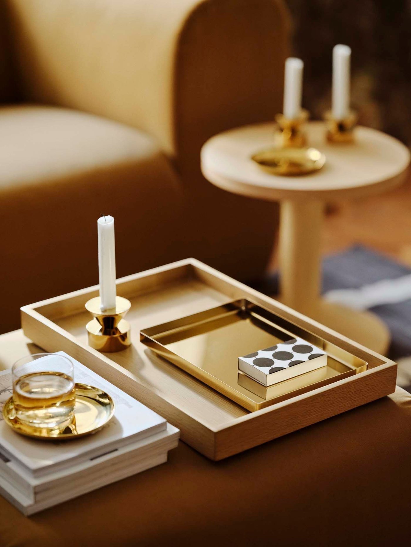 Brass-coloured accessories are coordinated on light wood trays and side tables.