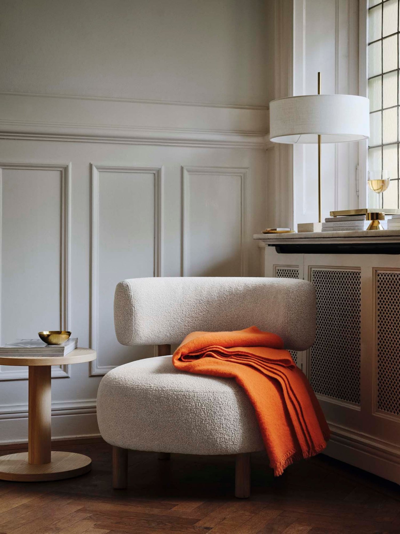 A bright orange throw on the seat of a beige STOCKHOLM 2025 armchair below a window.