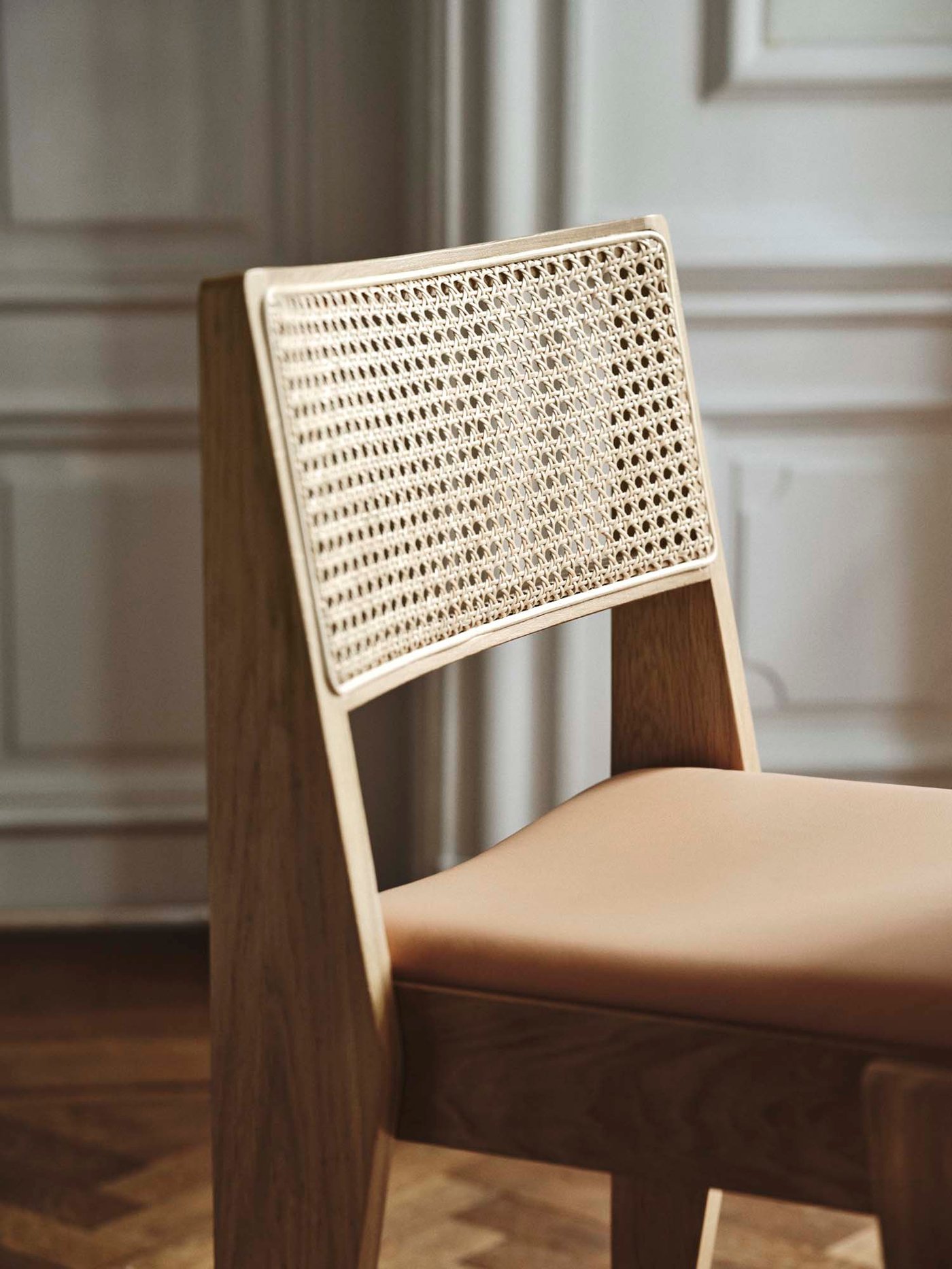 Close-up of dining chair with rattan back, oak veneer legs, and Seglora leather cushion