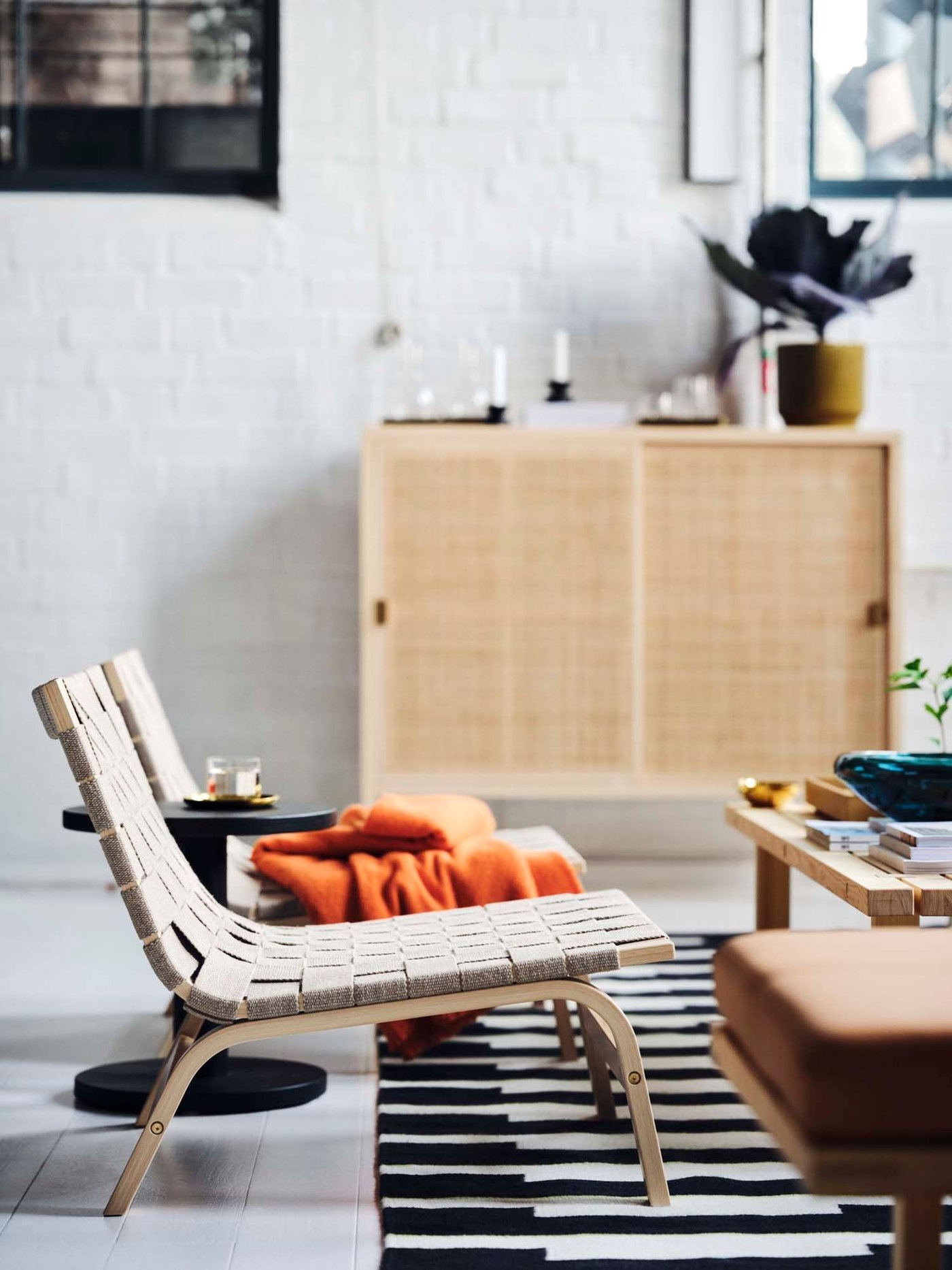 A white living room setting with light wood furniture on a black and white rug.