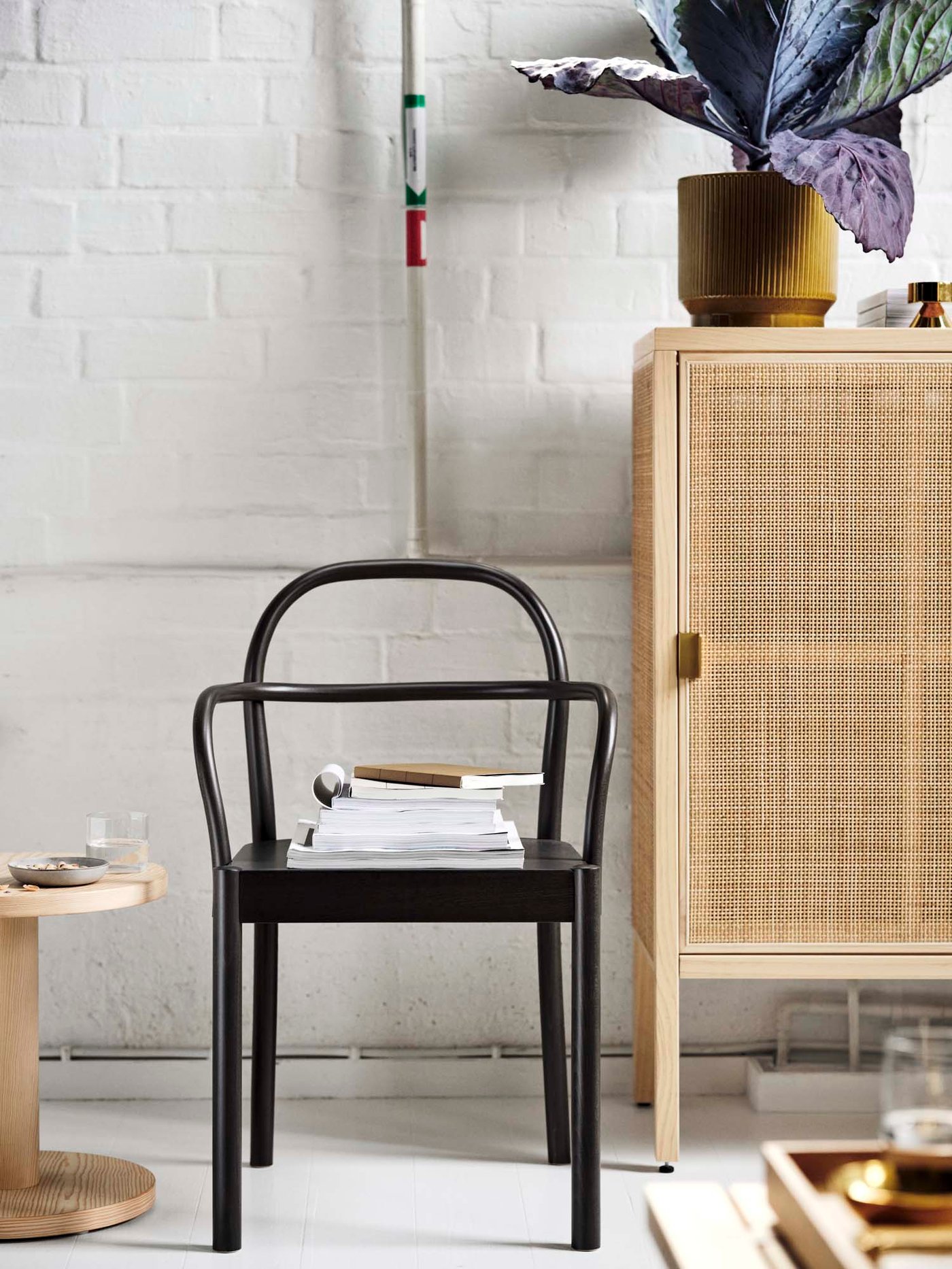 The bentwood chair in dark brown is standing in front of a rattan cabinet