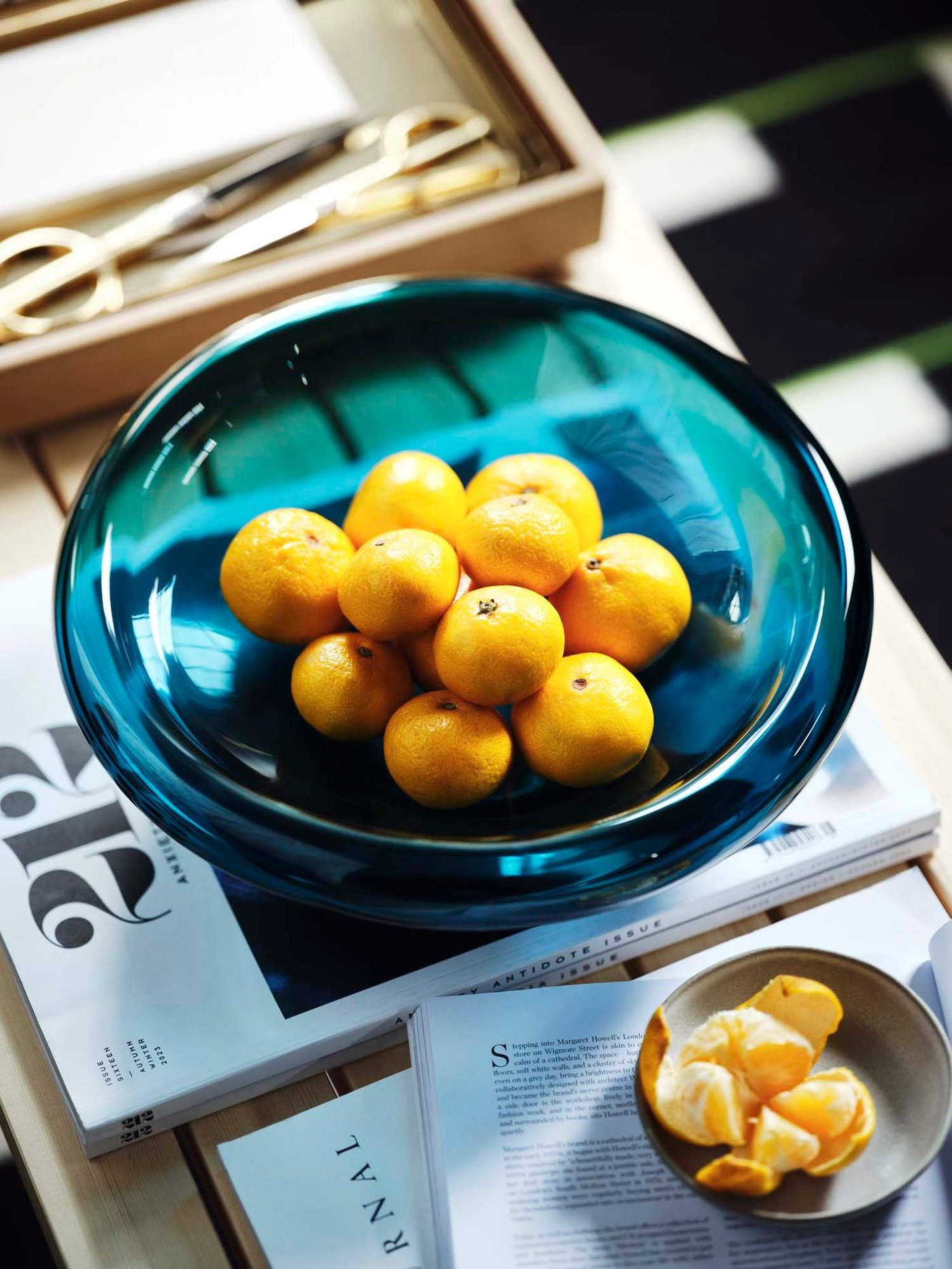 A blue glass dish filled with small orange fruit.