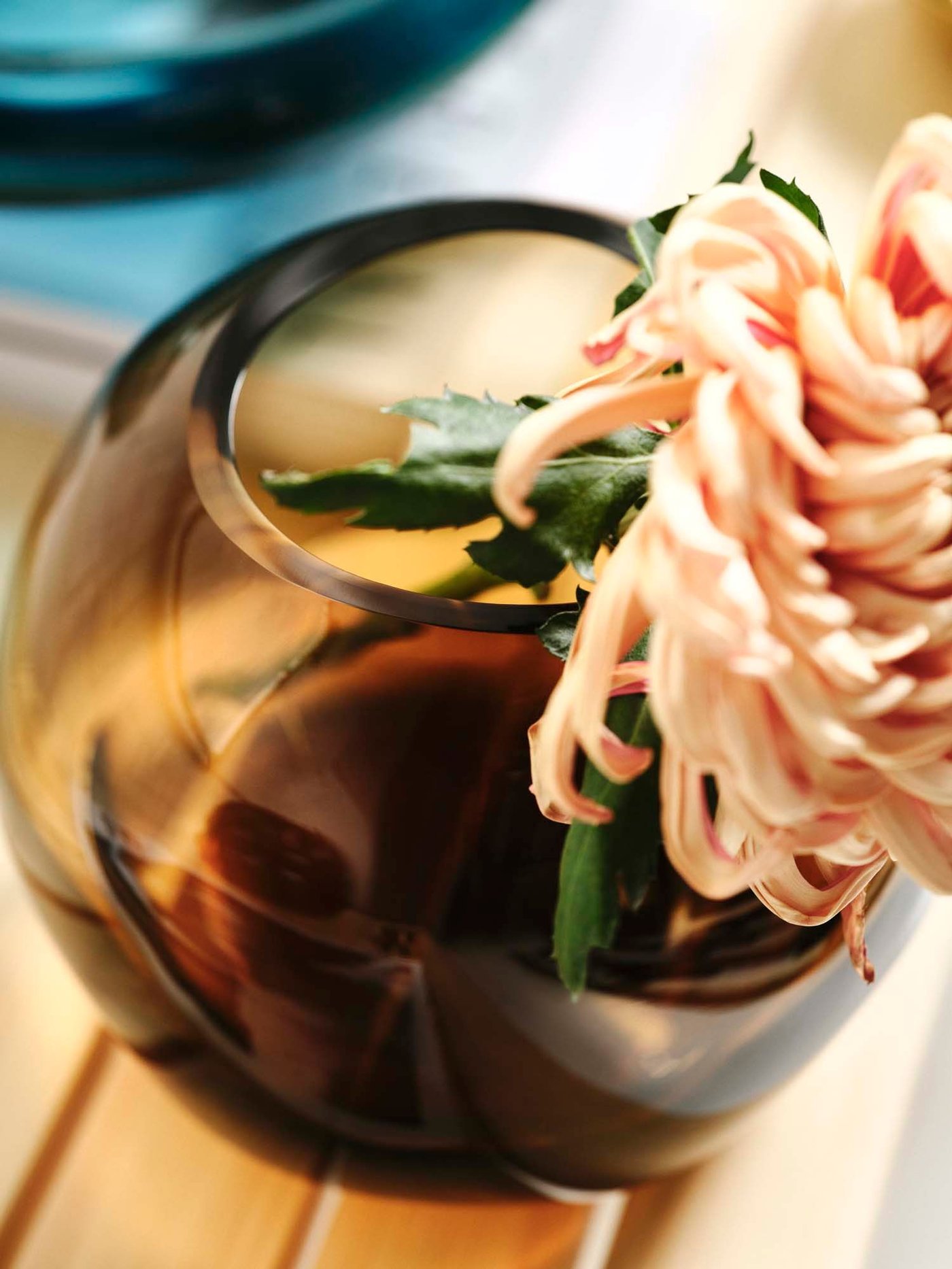 A close-up of a brown vase with a pretty pink flower.