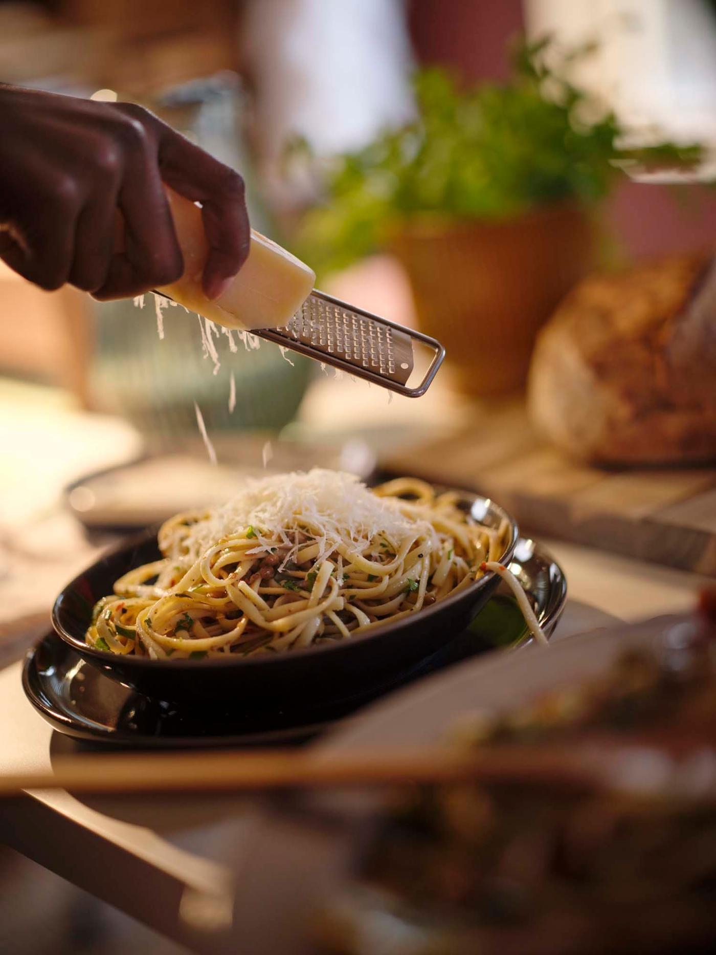 A bowl of pasta garnished with parmesan, served on rustic brown STOCKHOLM 2025 stoneware.