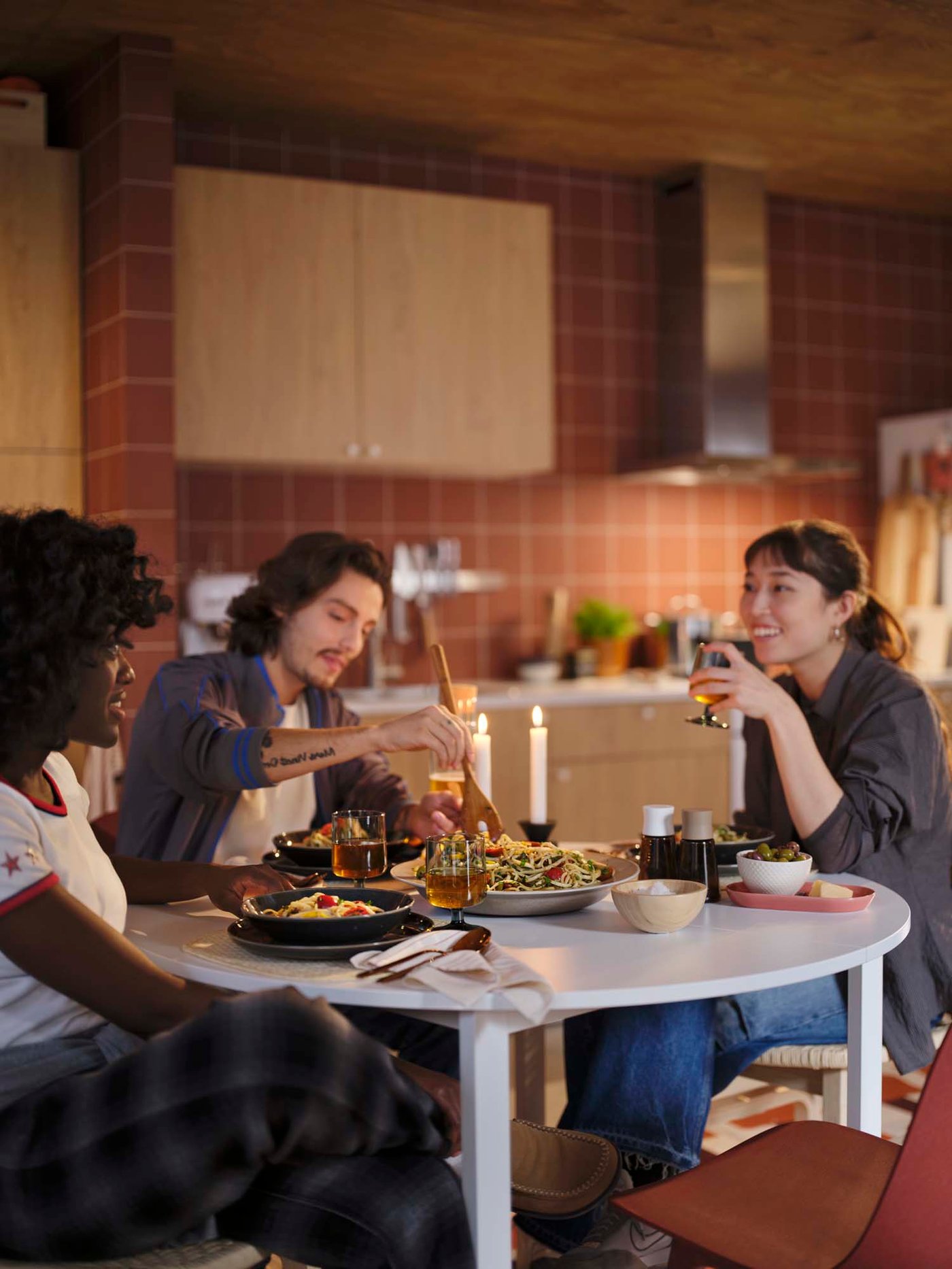 Three friends are sitting at a dining table and enjoying a home-cooked meal.
