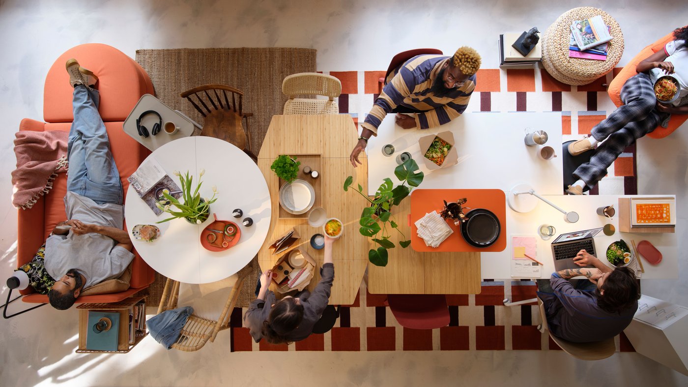 Five people sitting around several tables which have been joined together and carry out different tasks.