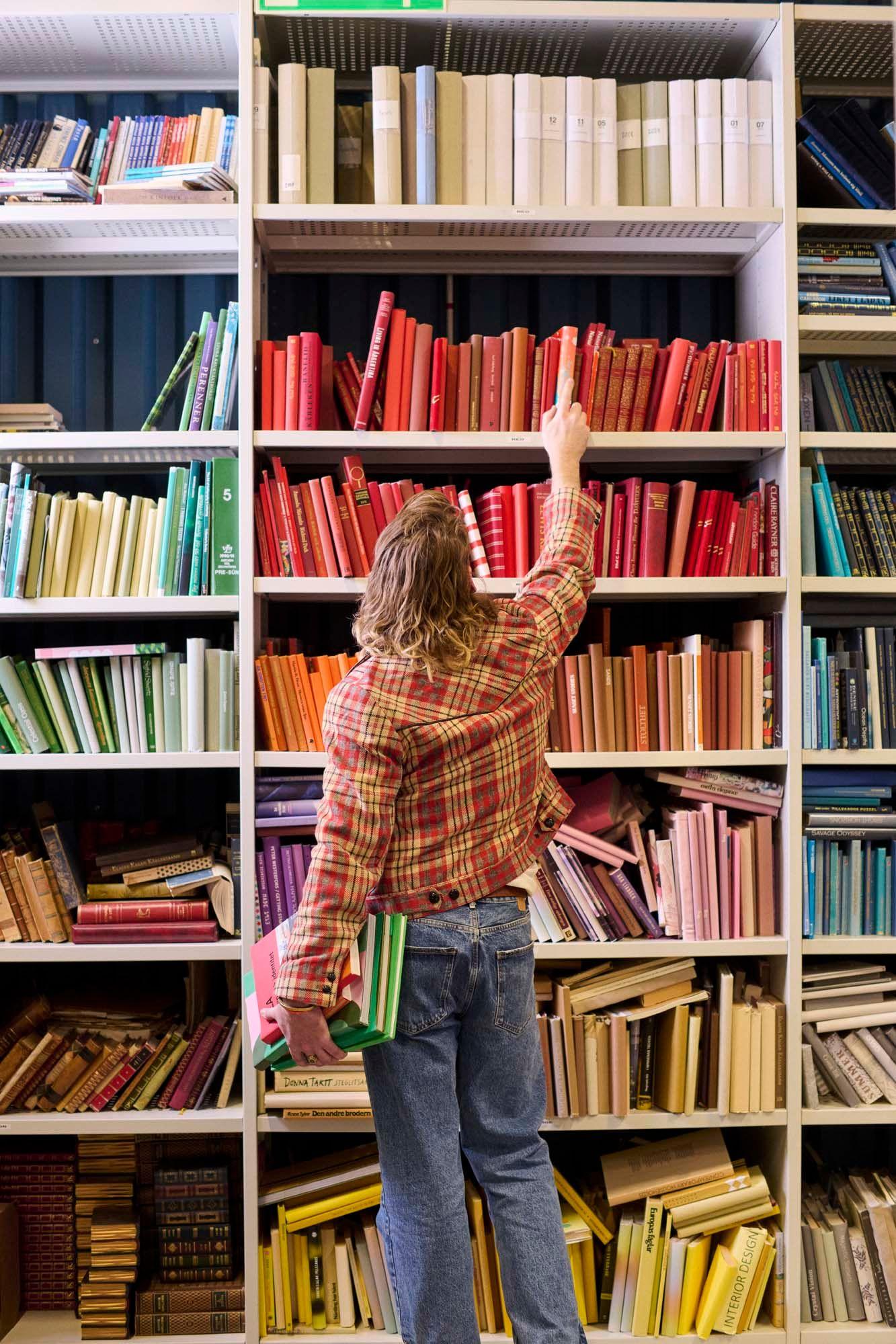 A person reaches up to take a book from a bookshelf.
