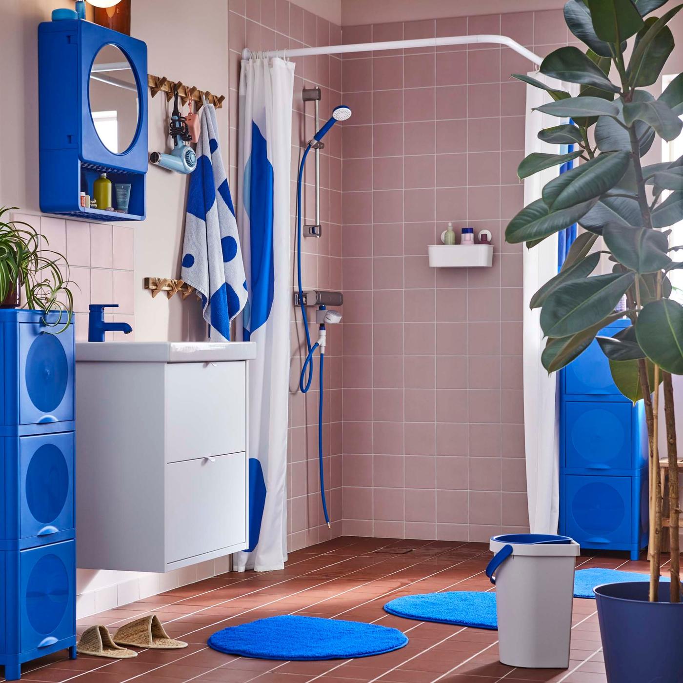 A pink, tiled bathroom with a big ficus plant and products from the BERGVATTNET collection.