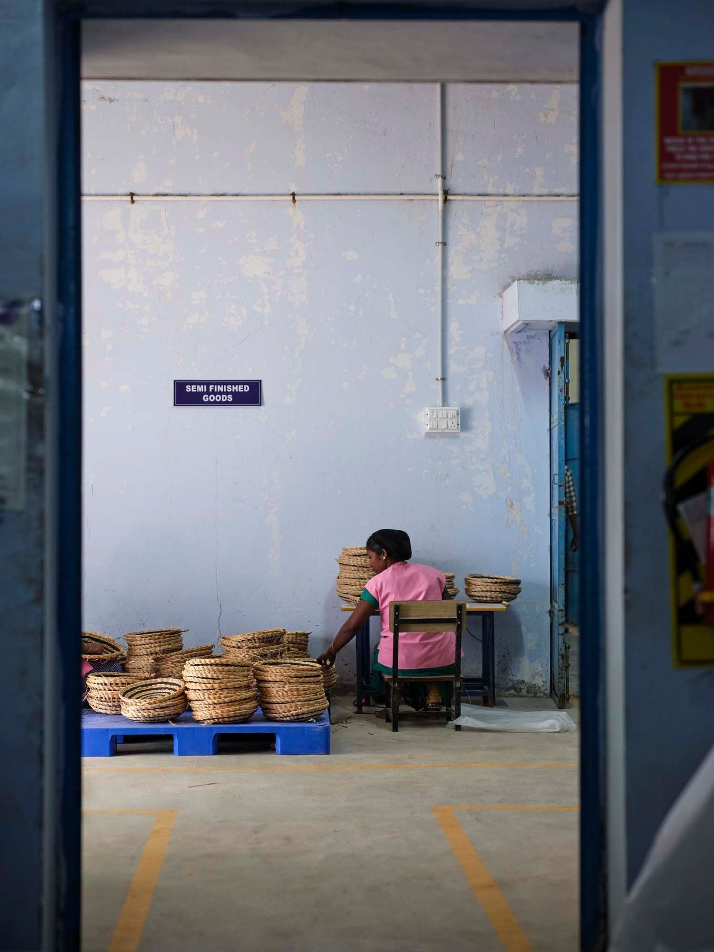 A person works with woven baskets in a room.