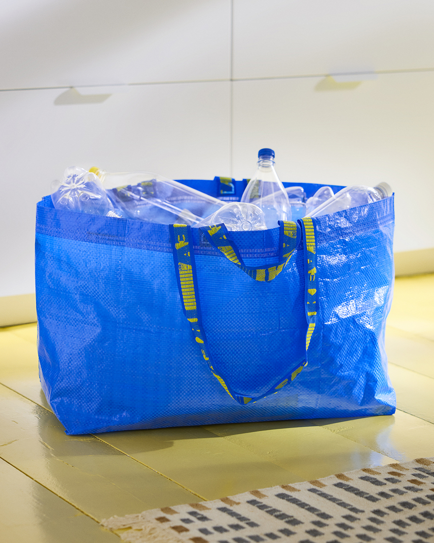 An updated FRAKTA bag carrying plastic bottles destined for the recycling bin.