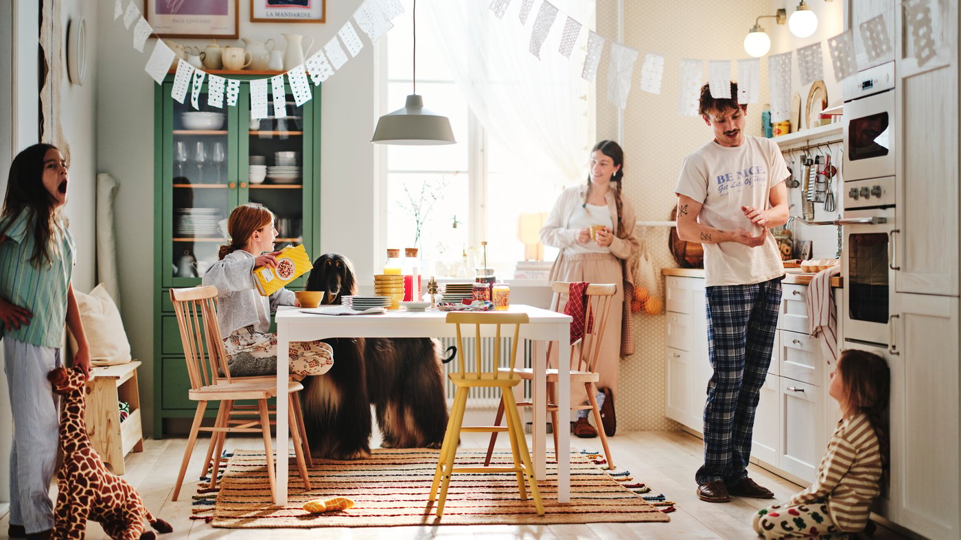 A family gathered in a bright, cheerful kitchen with a table set for breakfast.