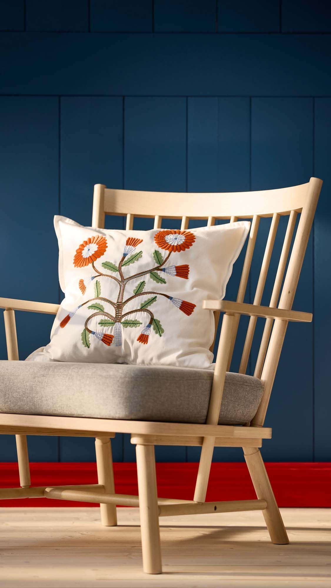 A PERSBOL armchair with a cushion in front of a dark blue wooden wall.