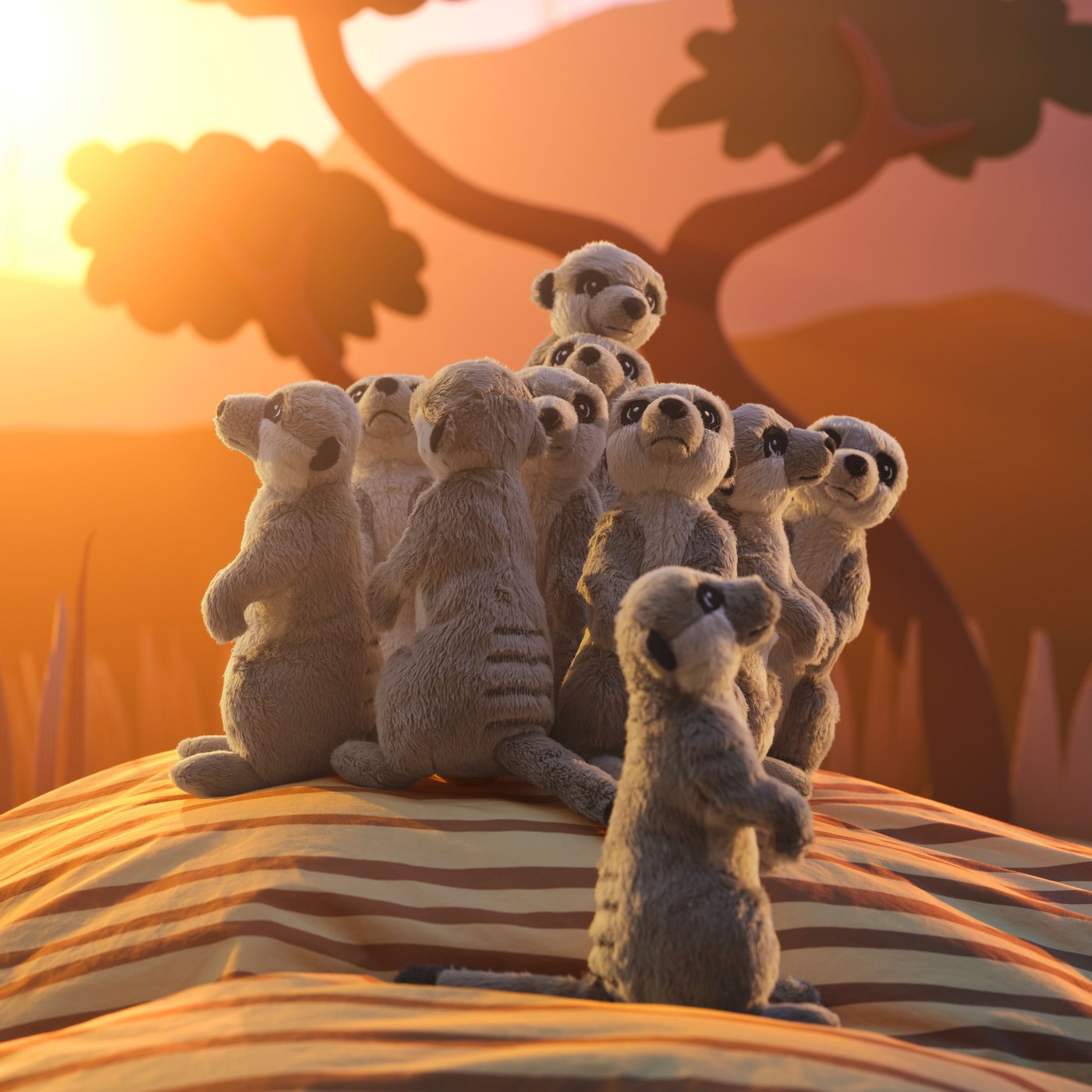 Several different meercat soft toys, all displayed with a backdrop inspired by the African savannah.