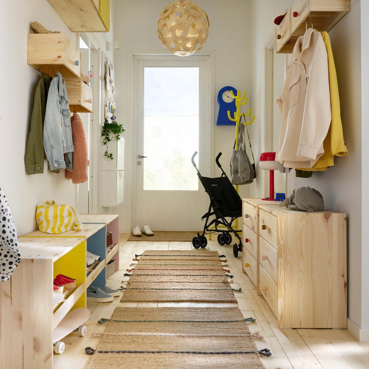 A white hallway of a family home with light wood storage on the floor and walls and colourful accents.