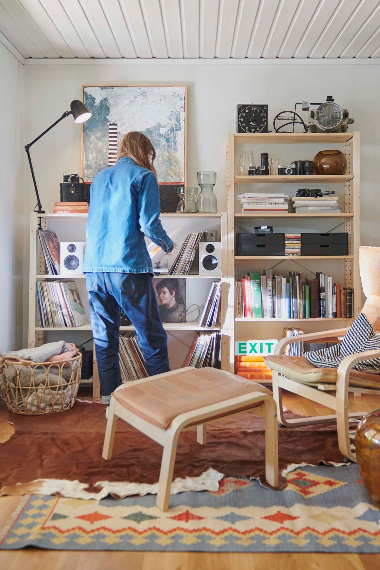 A person in a living room picks a vinyl record from an IVAR shelving unit filled with records, books and accessories.