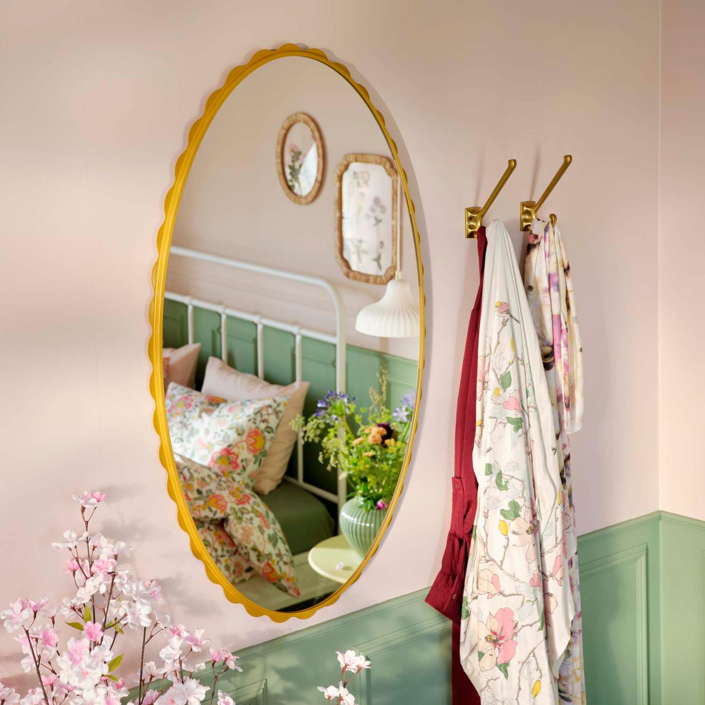Mirror with yellow flounced edge on a green and pink bedroom wall.