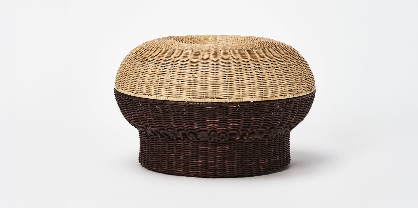 A natural and black rattan IKEA PS 20026 footstool against a pale grey background.