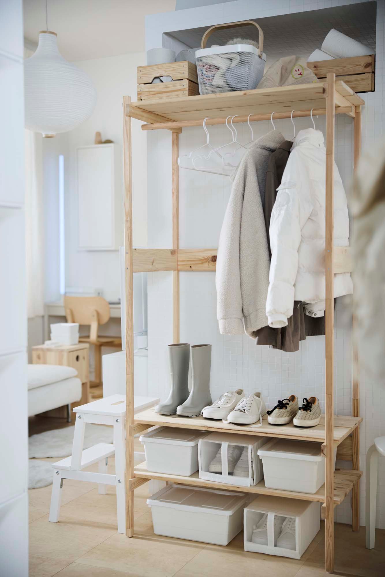 A light wood open wardrobe in front of a white wall.