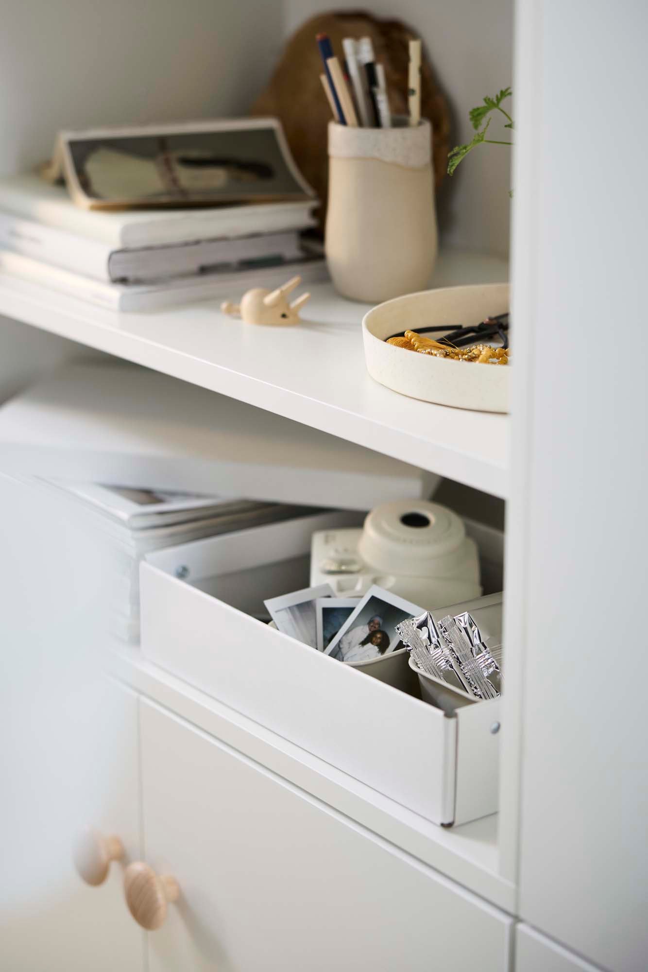 A white box filled with camera equipment resting on a white shelf.