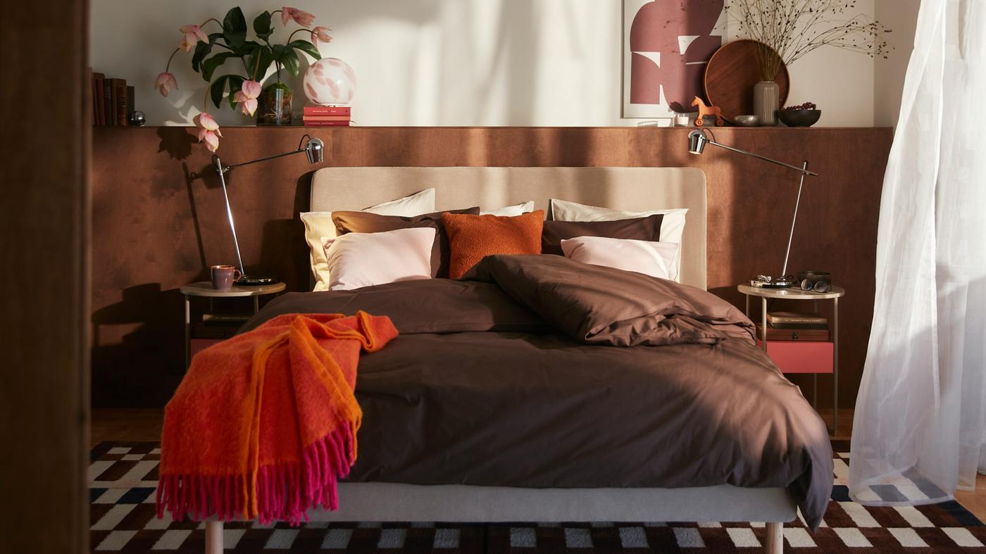 A relaxing brown, cream and orange bedroom. The sun casts shadows on the wall.