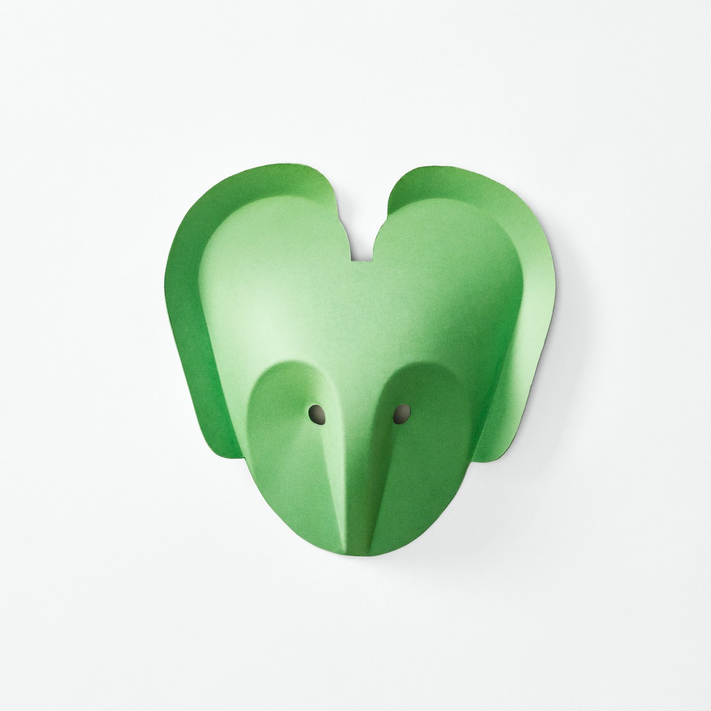 Close-up of a green wall hook shaped like an abstract animal head with two small holes and a protruding nose.